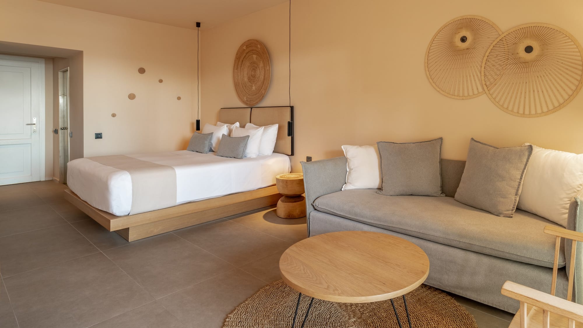 Neutral hotel suite with bed, sofa, coffee table, and contemporary decor.