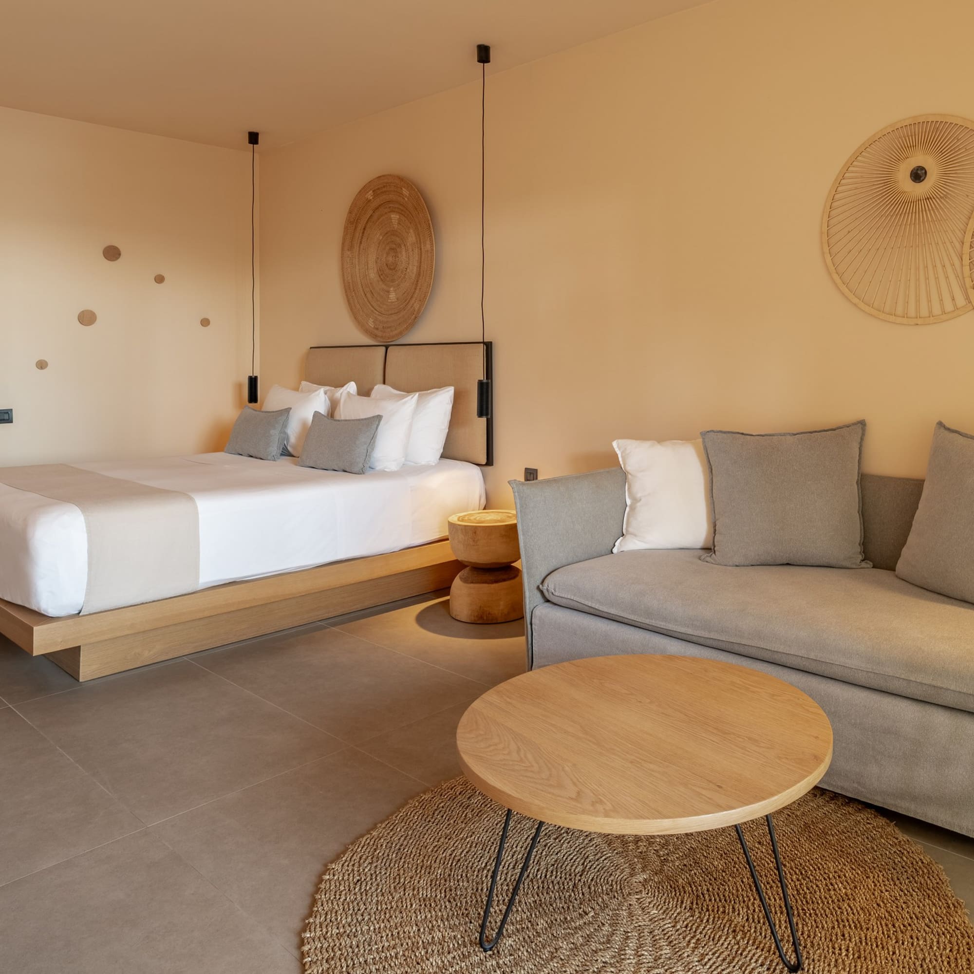 Neutral hotel suite with bed, sofa, coffee table, and contemporary decor.