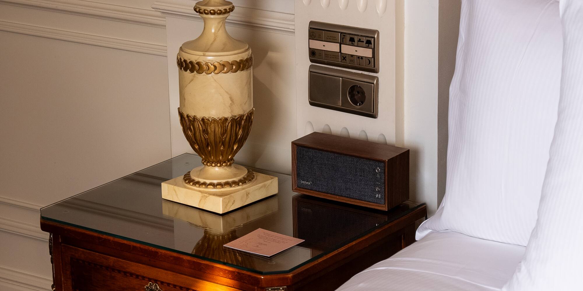 a lamp on a table next to a bed