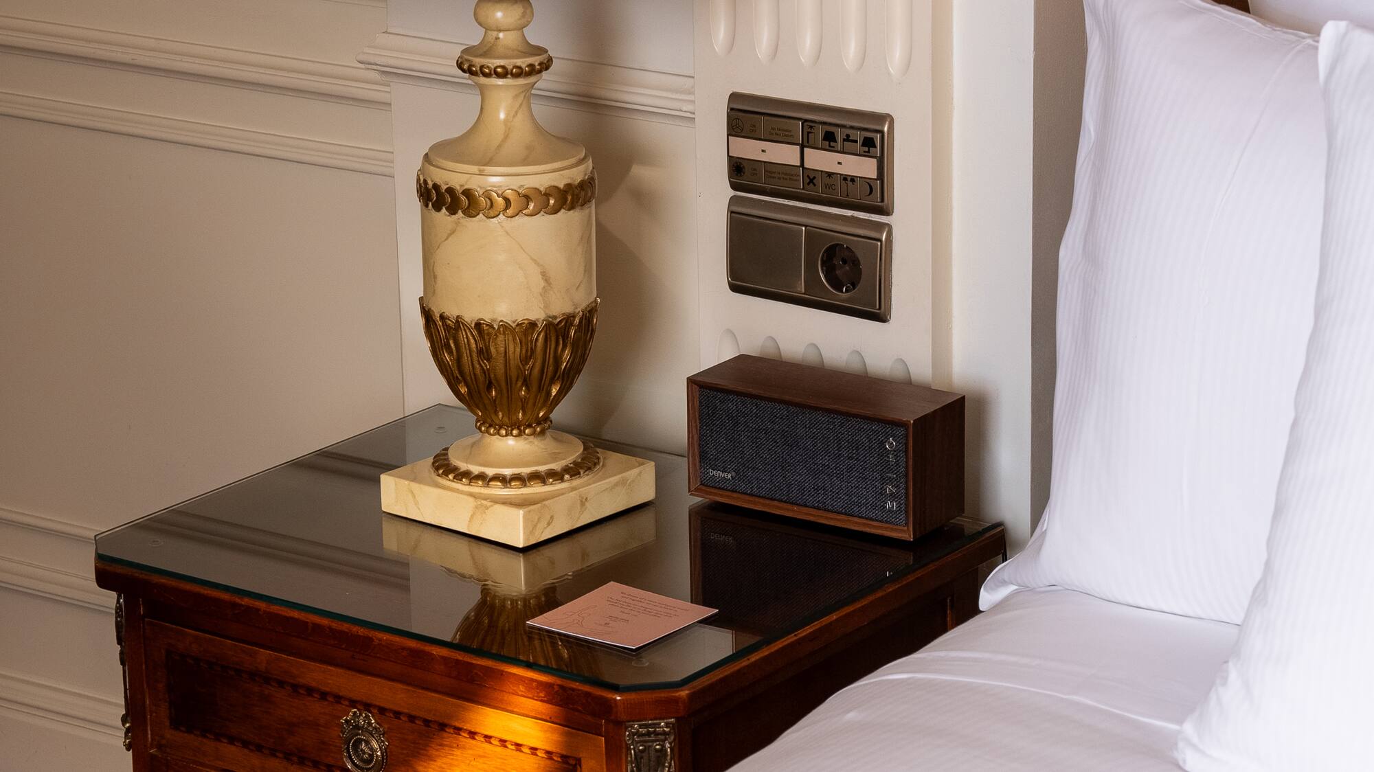 a lamp on a table next to a bed