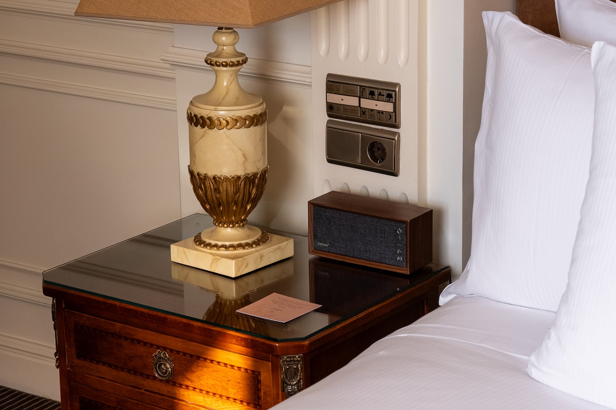 a lamp on a table next to a bed