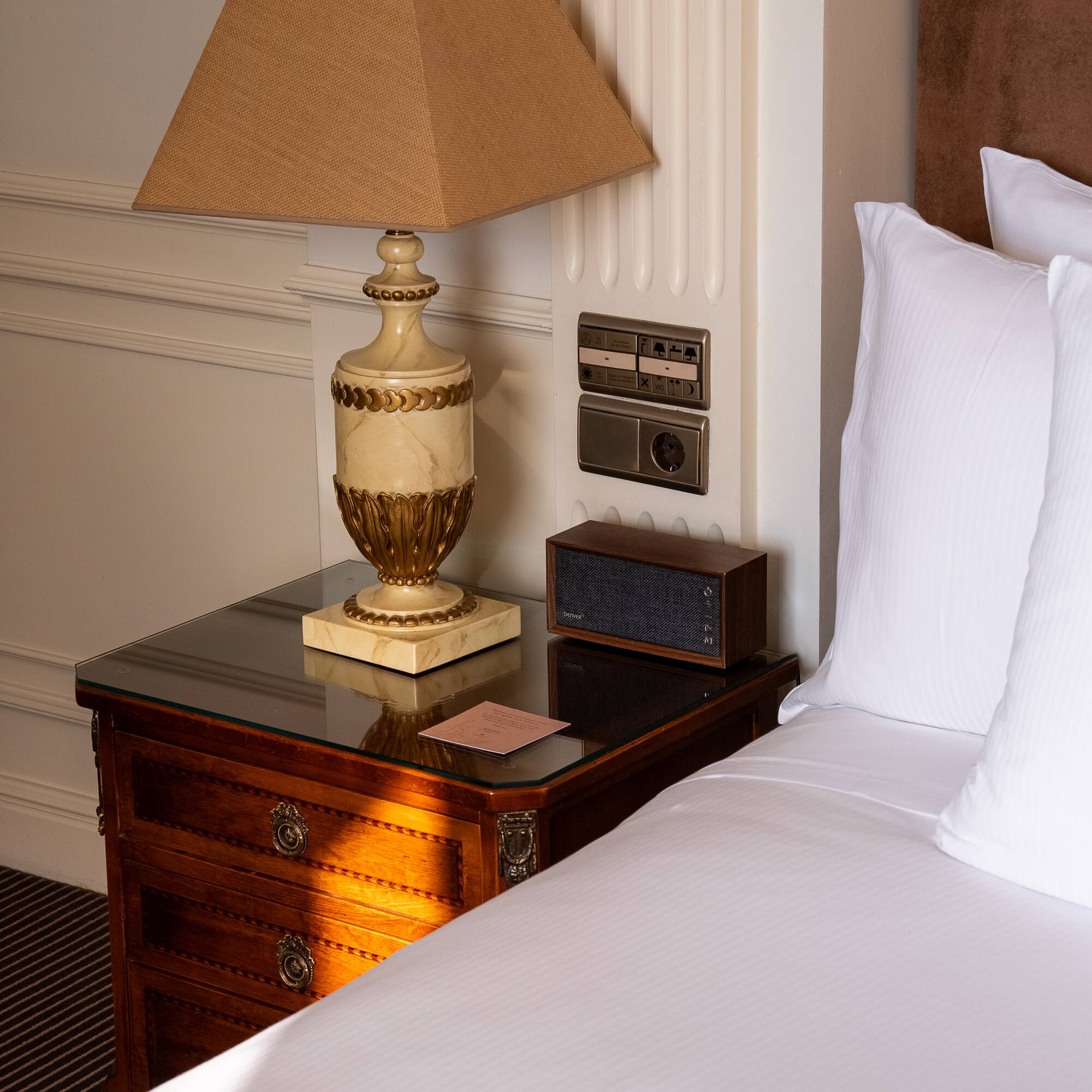 a lamp on a table next to a bed