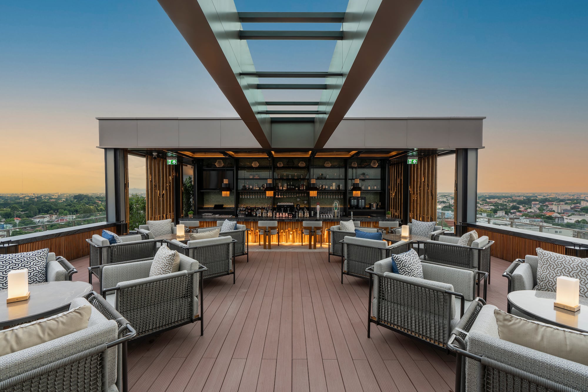 Modern rooftop bar with lounge seating overlooking city at sunset.