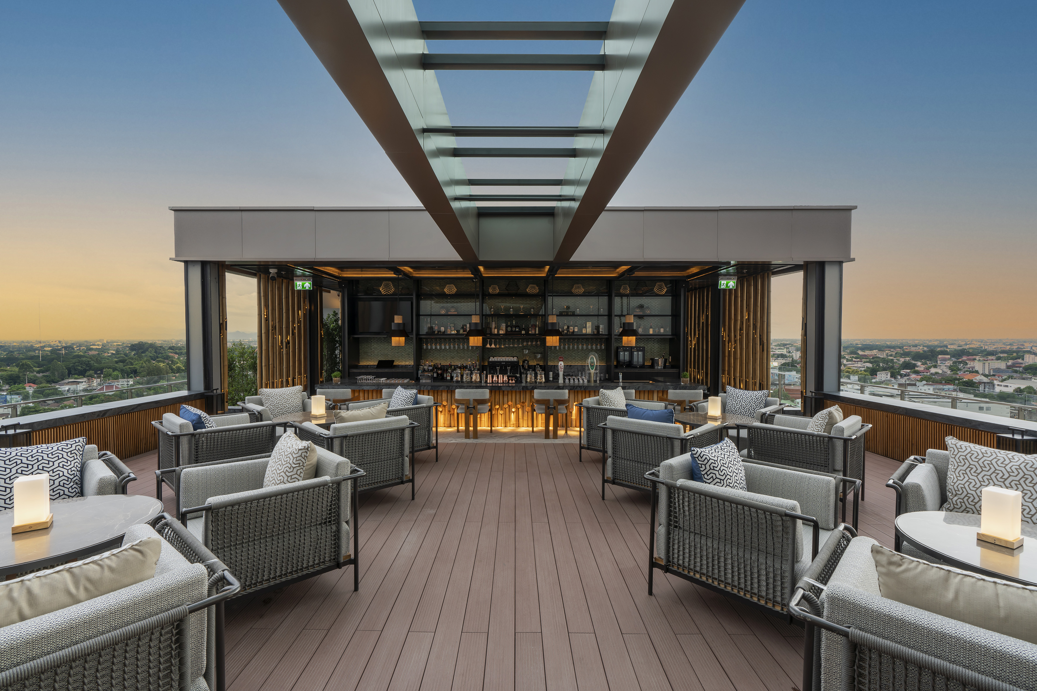 Modern rooftop bar with lounge seating overlooking city at sunset.