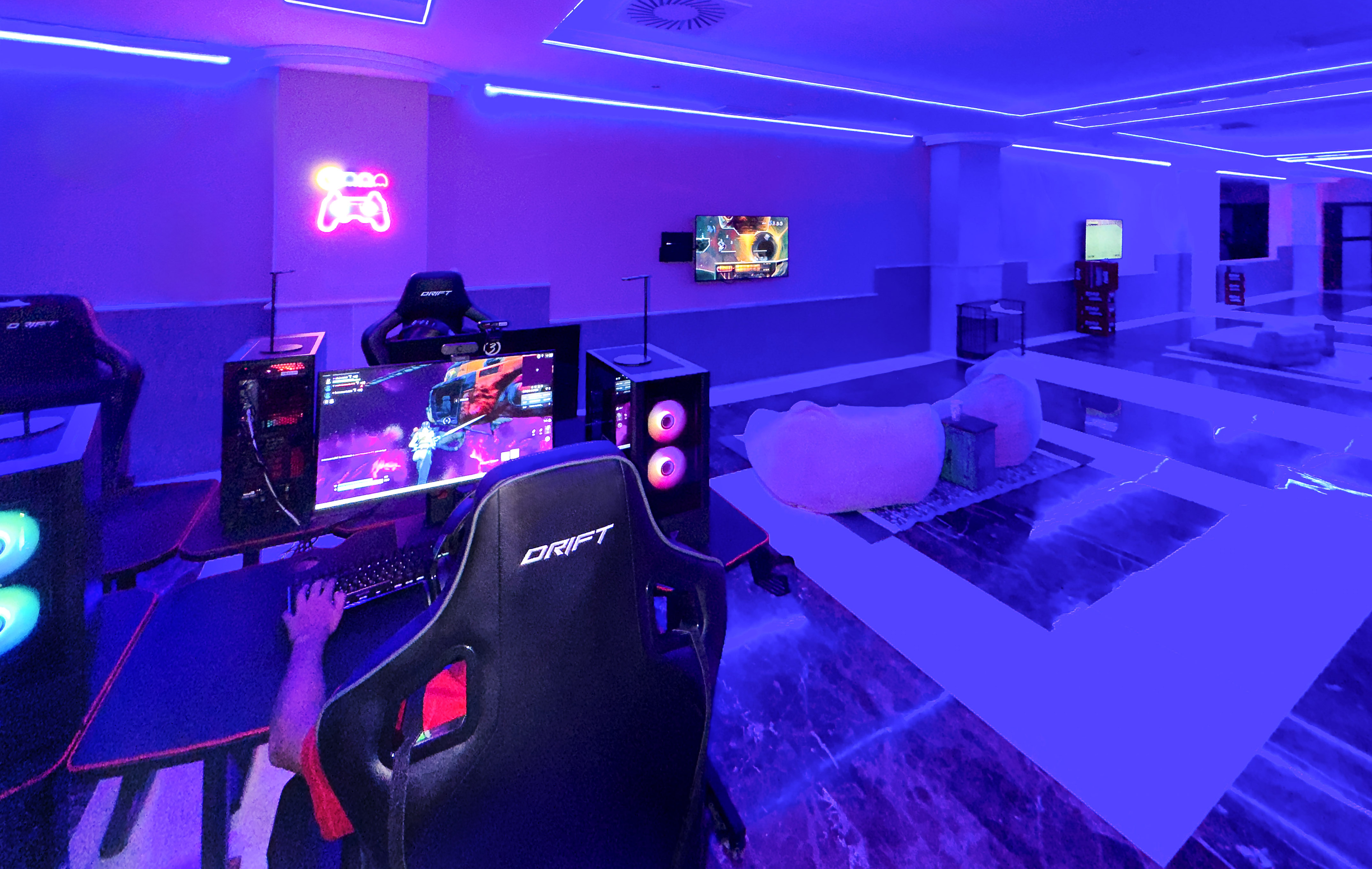 Esports gaming room with blue neon light, gamer at PC setup, controller sign.