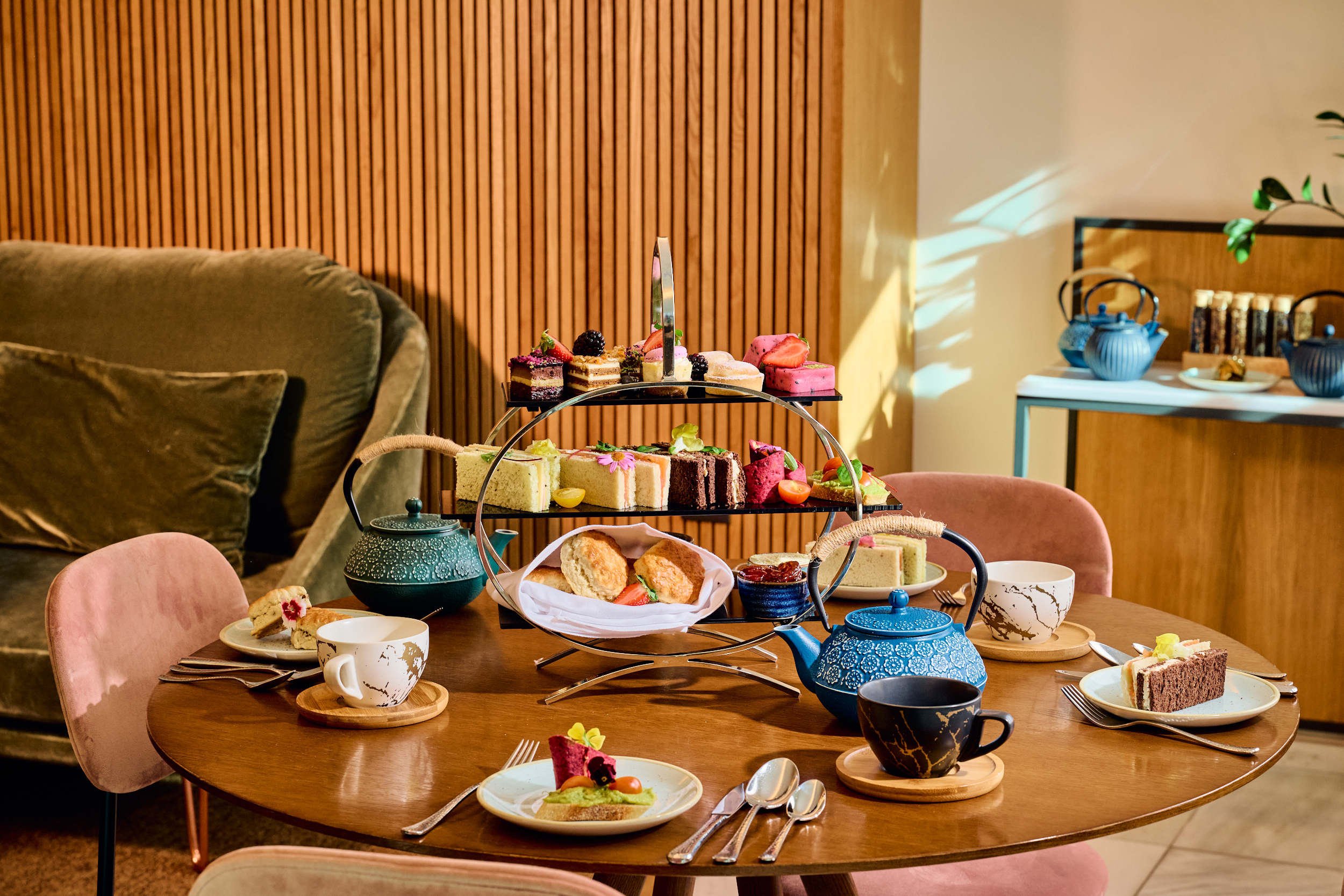 Afternoon tea with tiered stand of cakes, sandwiches, scones, and teapots.