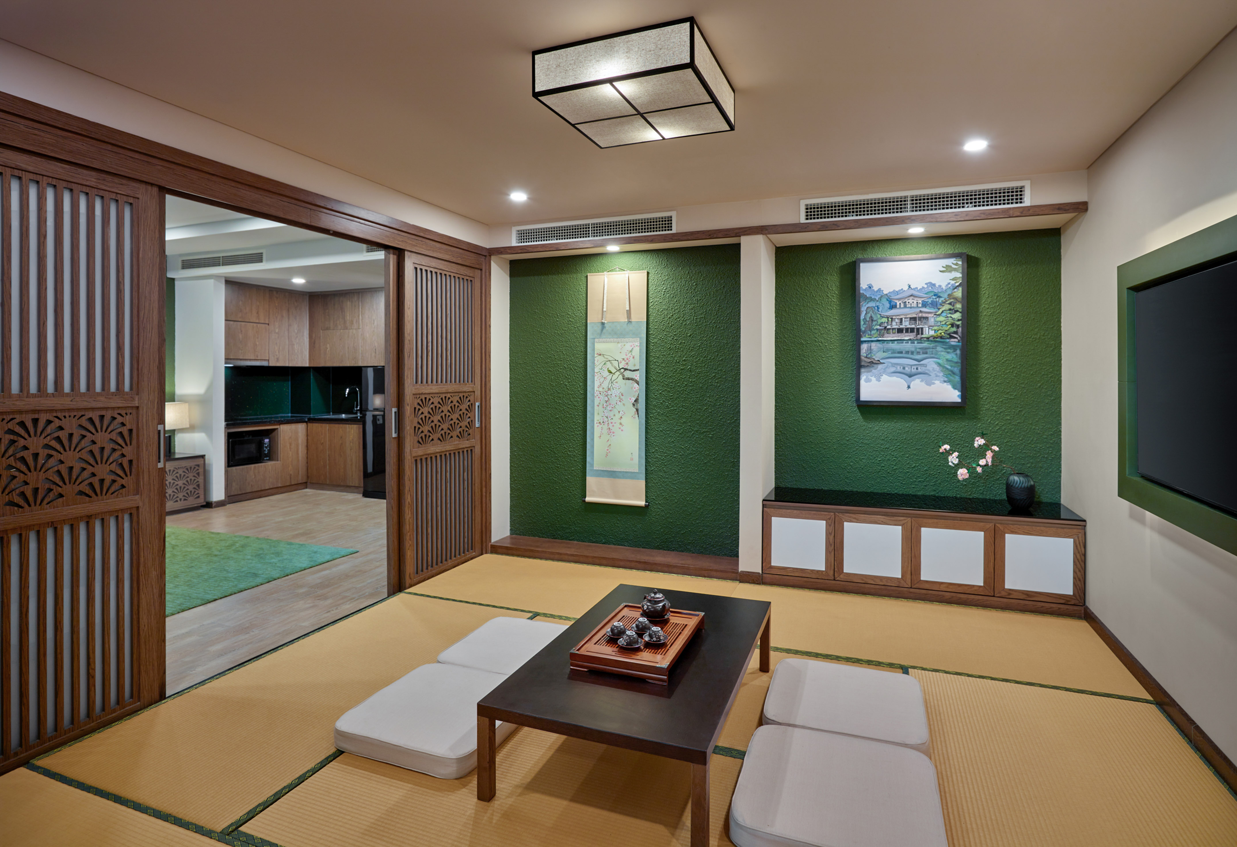 Japanese tatami living room with low tea table, green wall, and sliding doors.