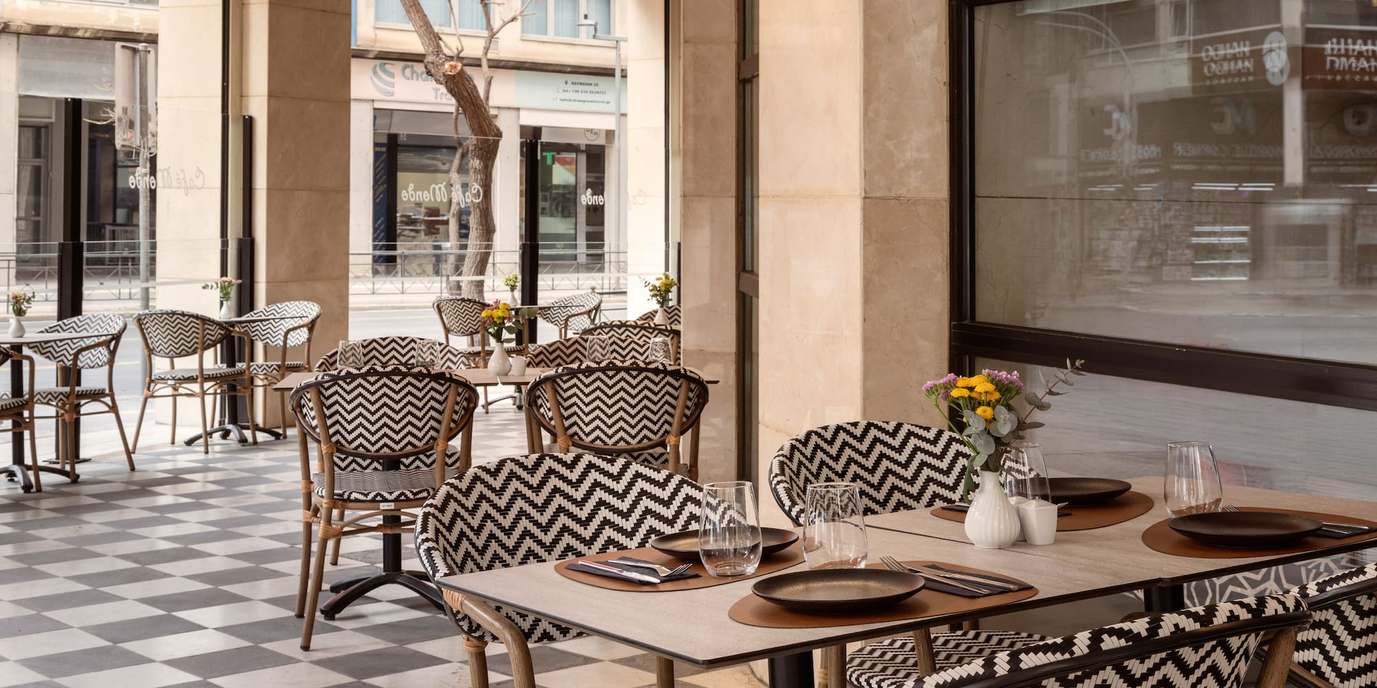 Stylish outdoor cafe patio with chevron chairs, checkered floor, and tables.