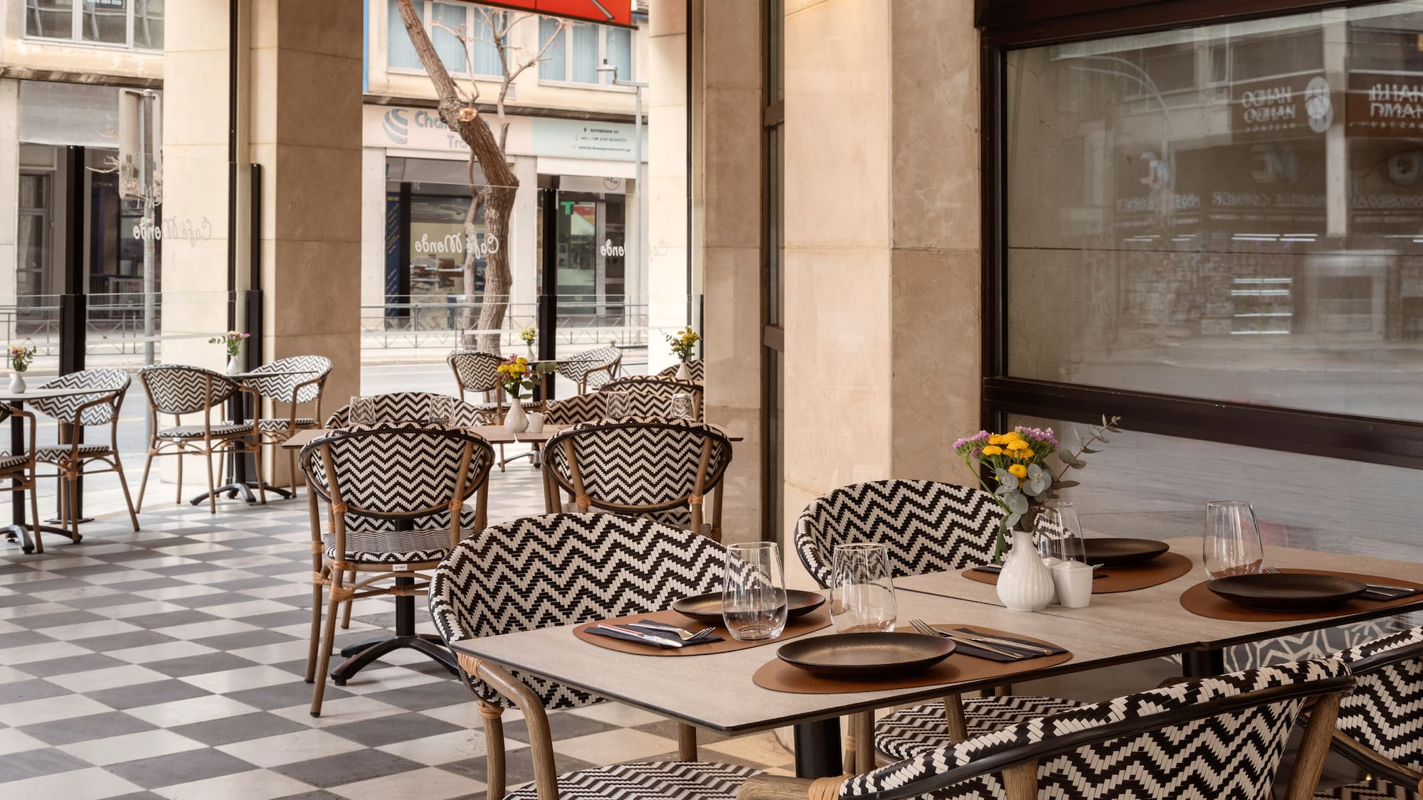 Stylish outdoor cafe patio with chevron chairs, checkered floor, and tables.