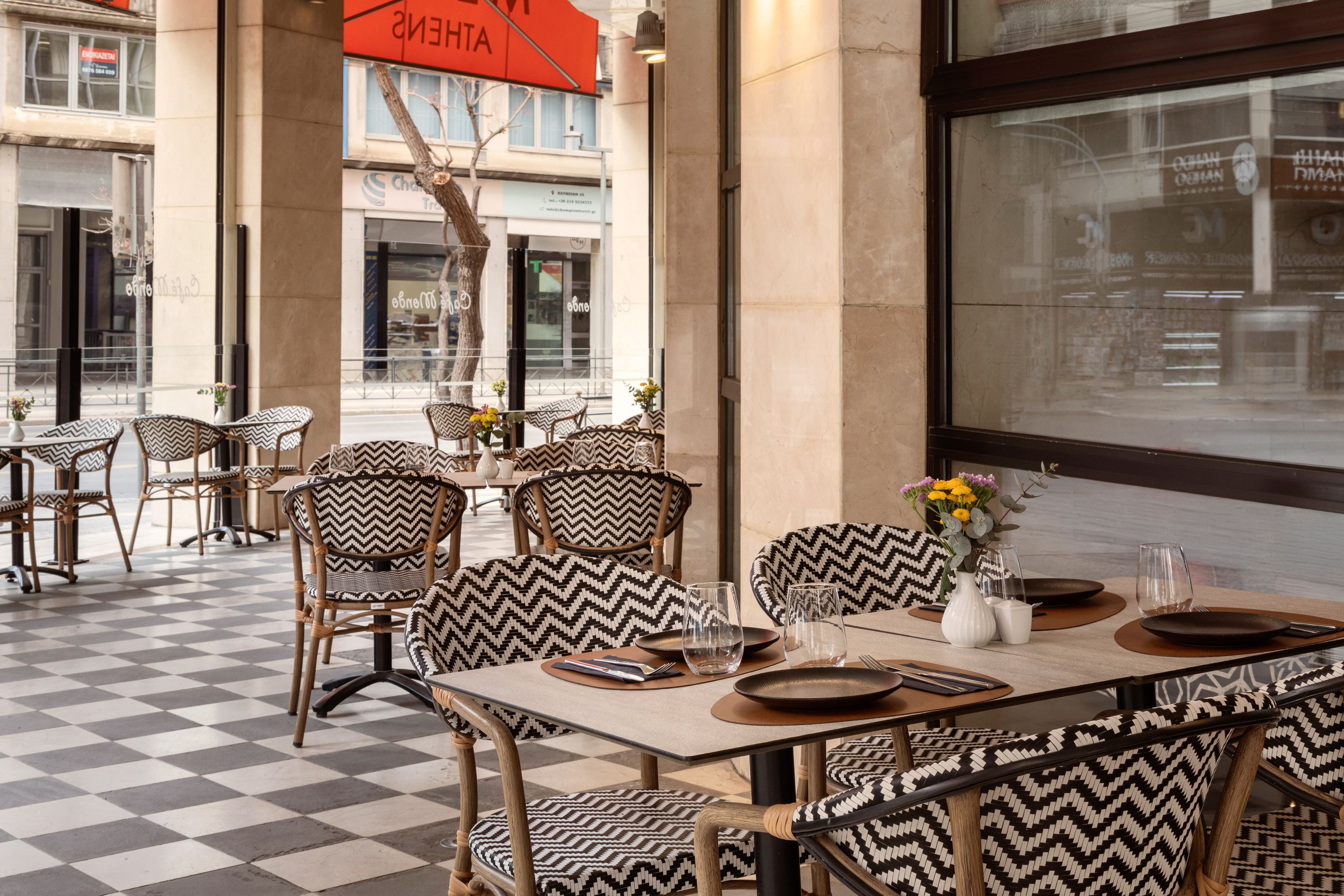 Stylish outdoor cafe patio with chevron chairs, checkered floor, and tables.