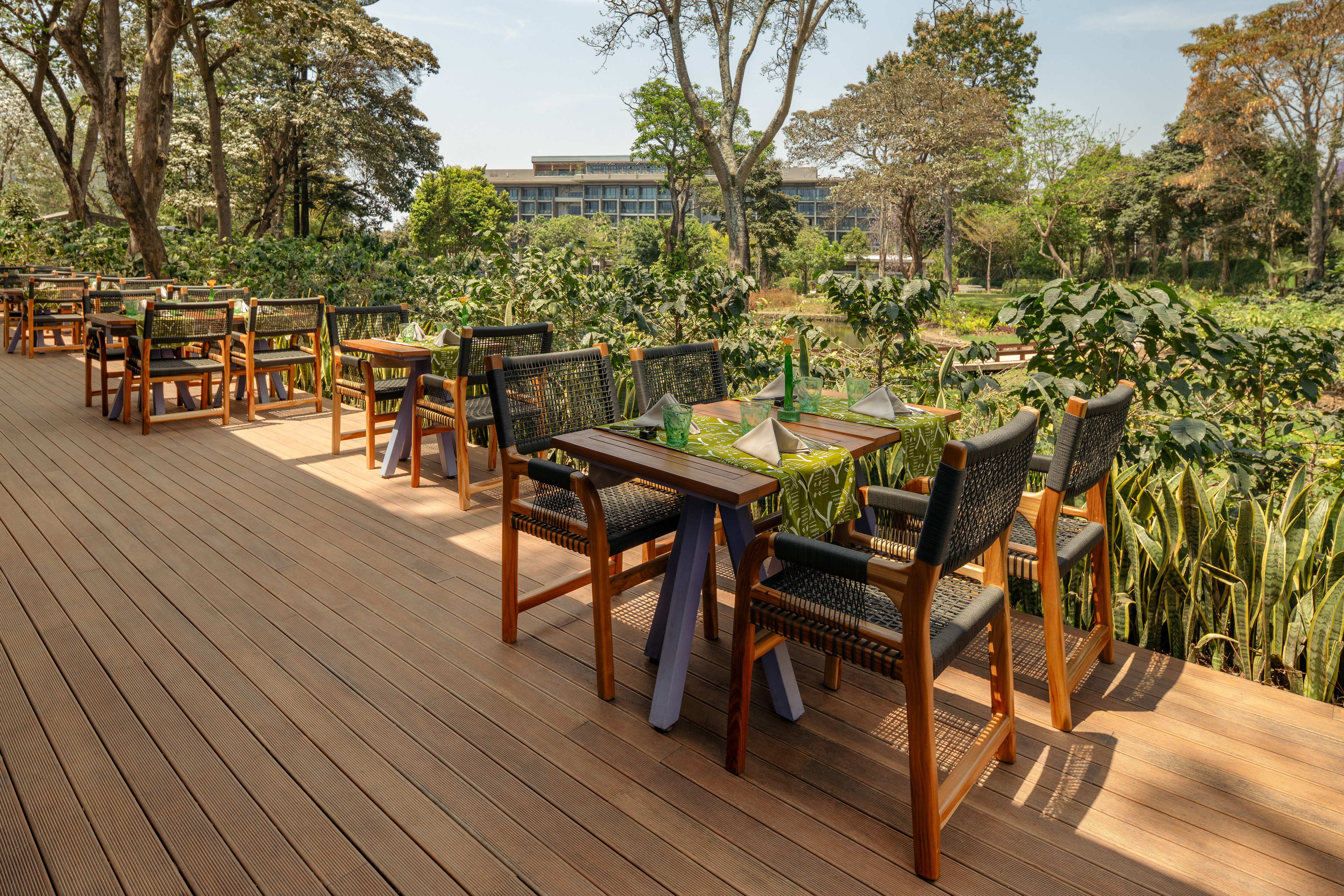 Al fresco dining on wooden deck with tables, chairs, lush garden, resort.