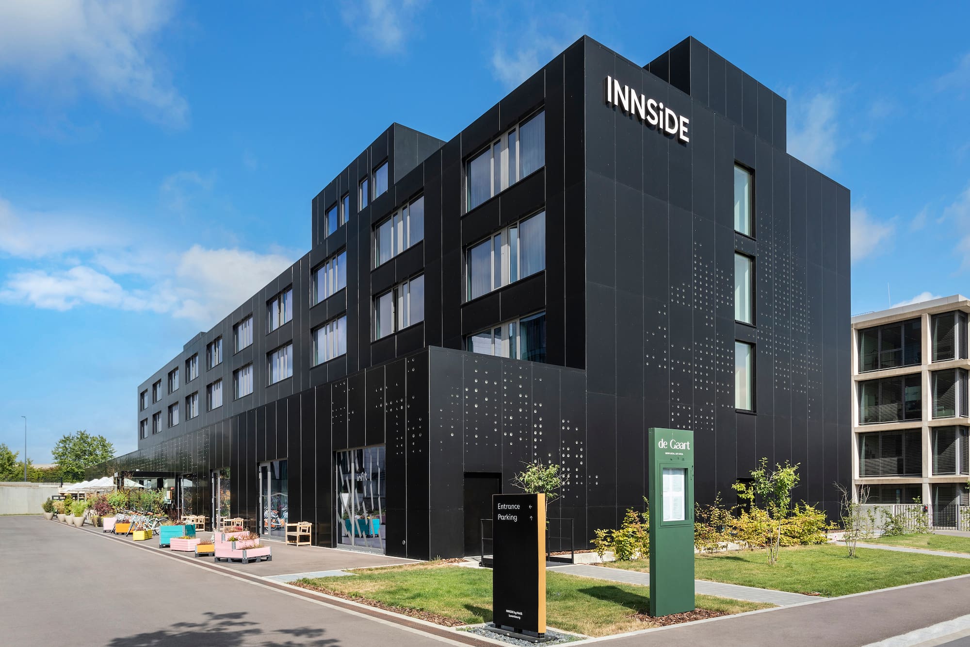 INNSIDE hotel with modern black facade, bright windows, and outdoor area.