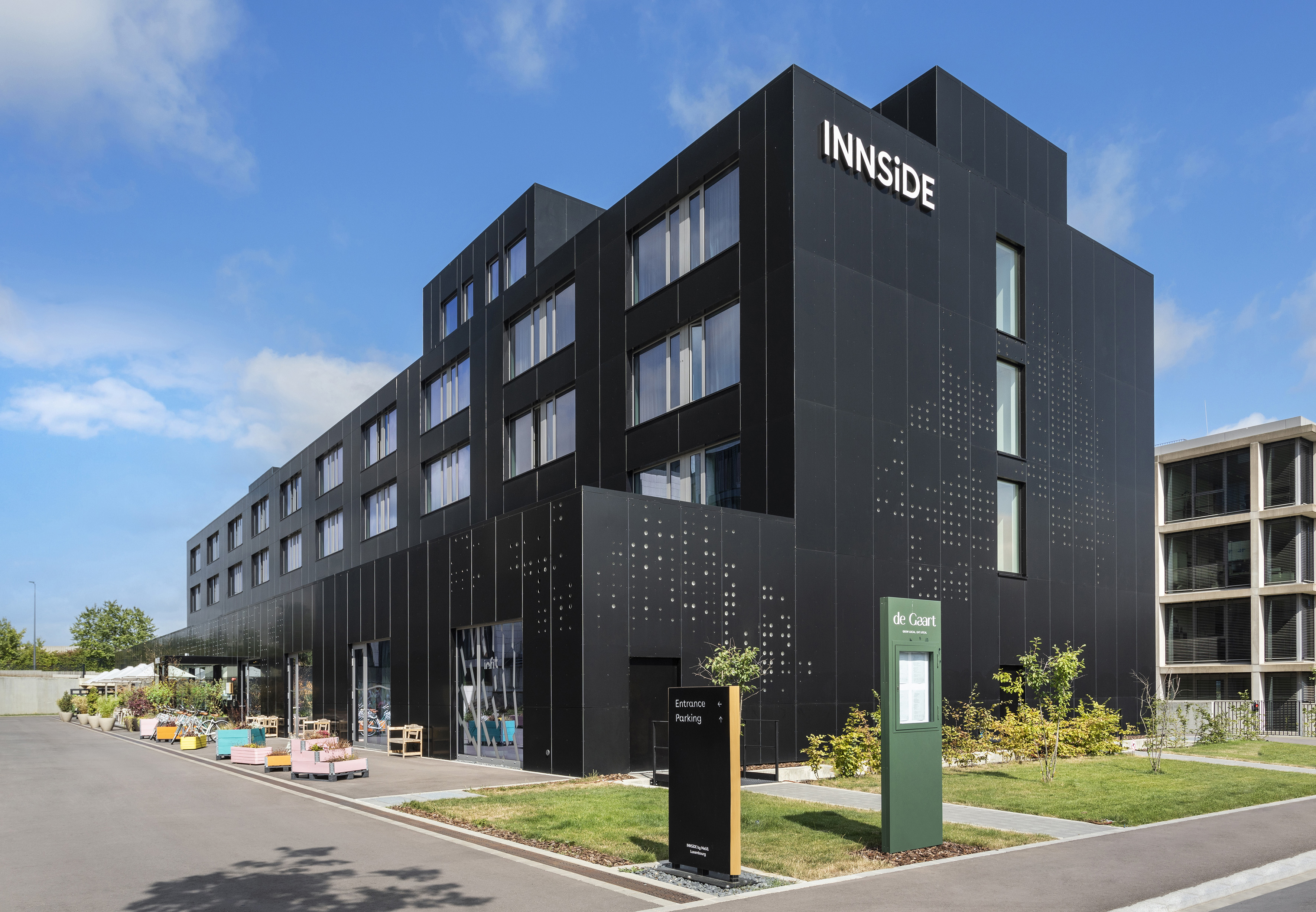 INNSIDE hotel with modern black facade, bright windows, and outdoor area.