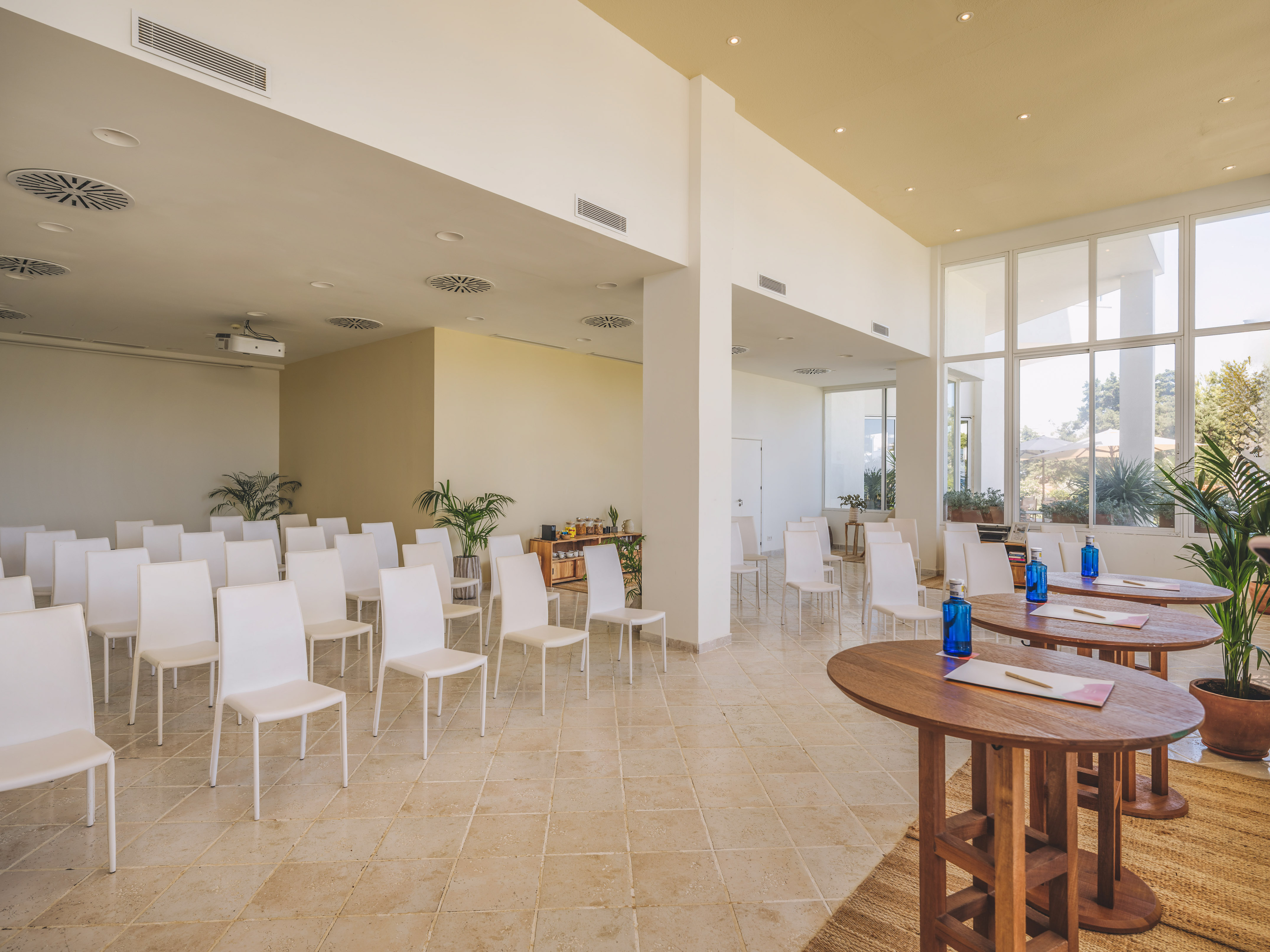 Bright modern conference room setup with white chairs, high tables, and projector.