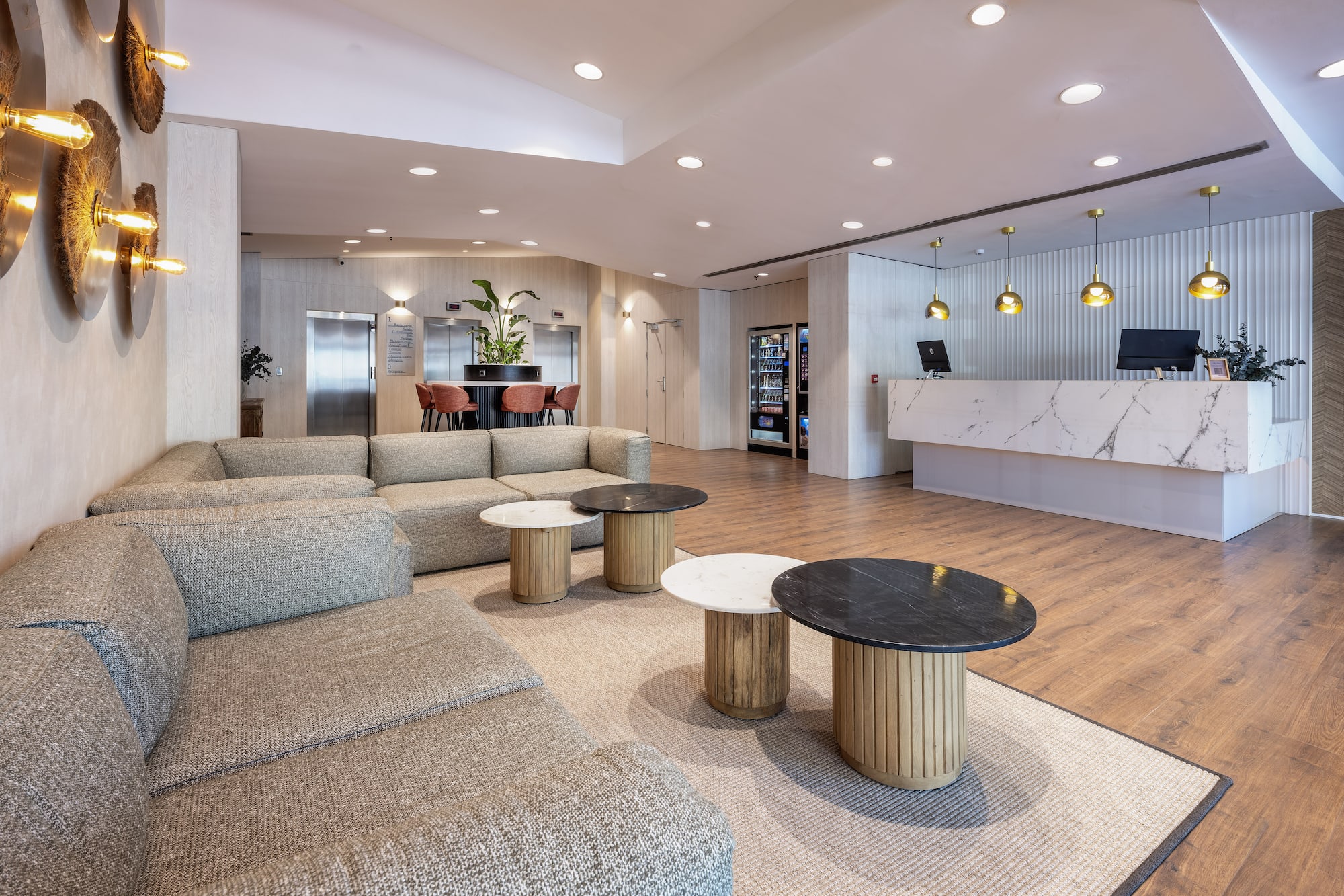Modern hotel lobby with a marble reception, spacious sofa lounge, and coffee tables.