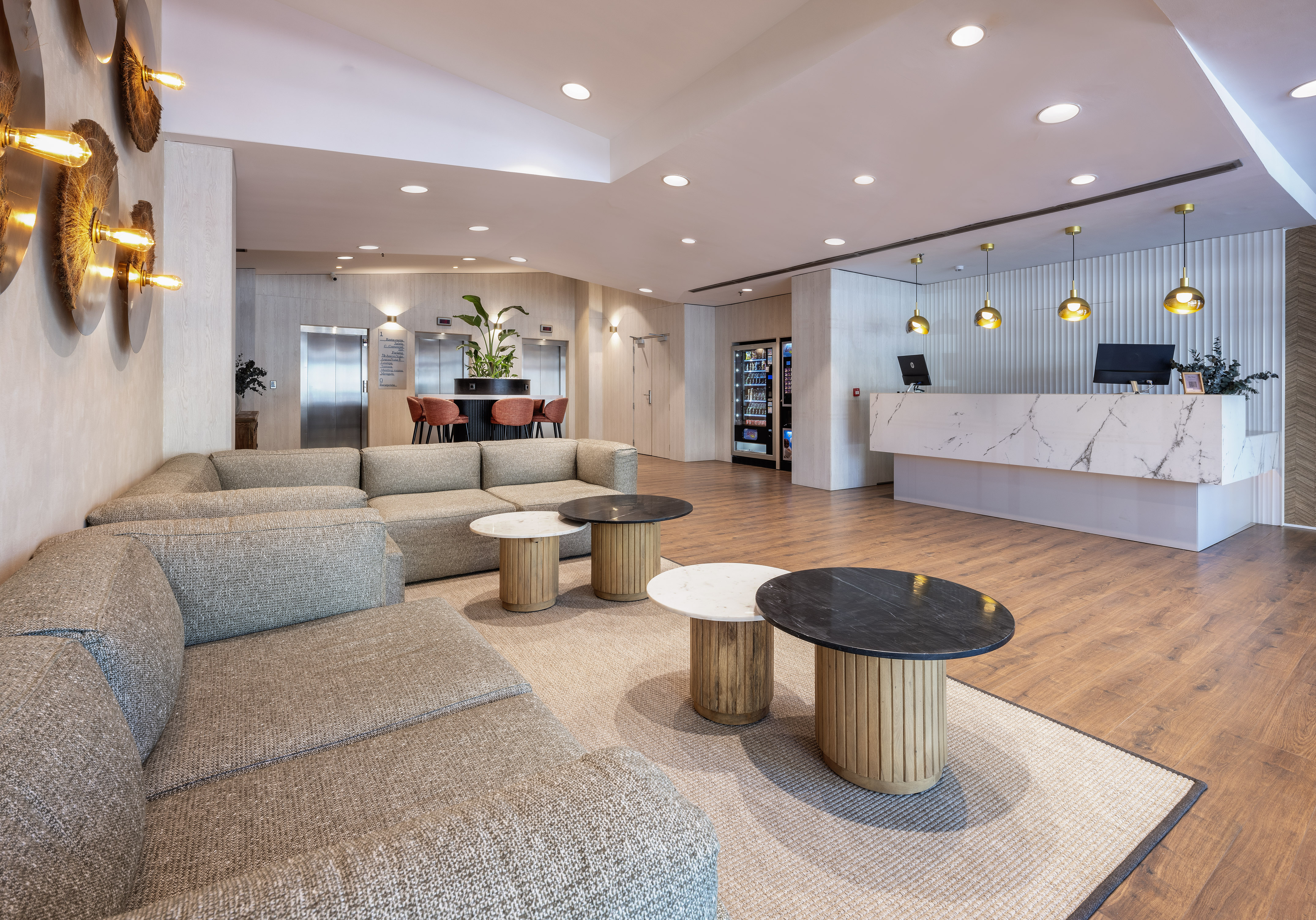 Modern hotel lobby with a marble reception, spacious sofa lounge, and coffee tables.