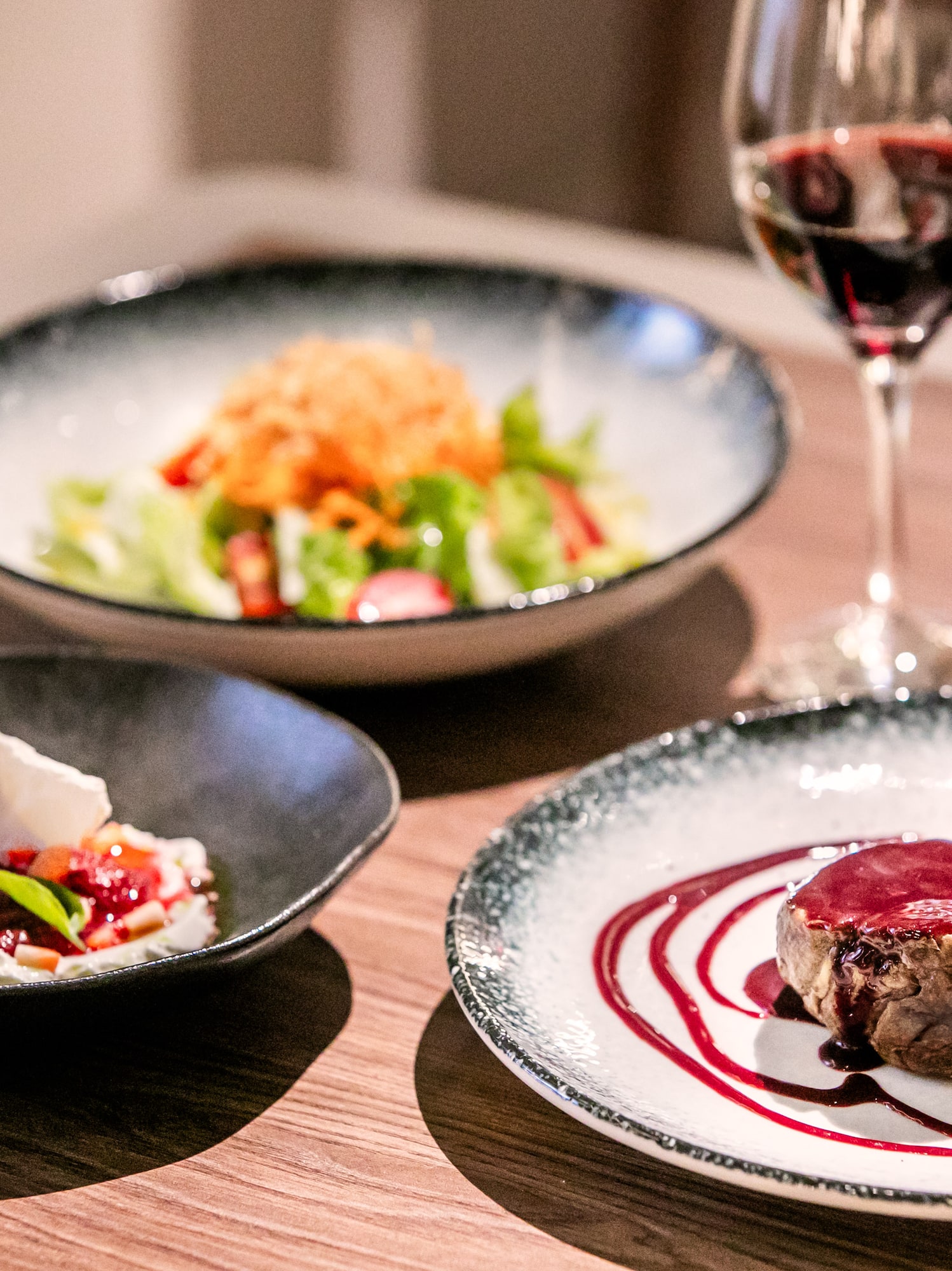 a table with plates of food and a glass of wine