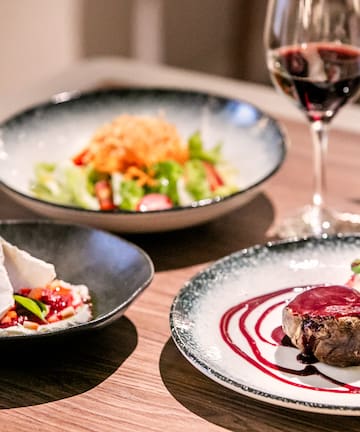 a table with plates of food and a glass of wine