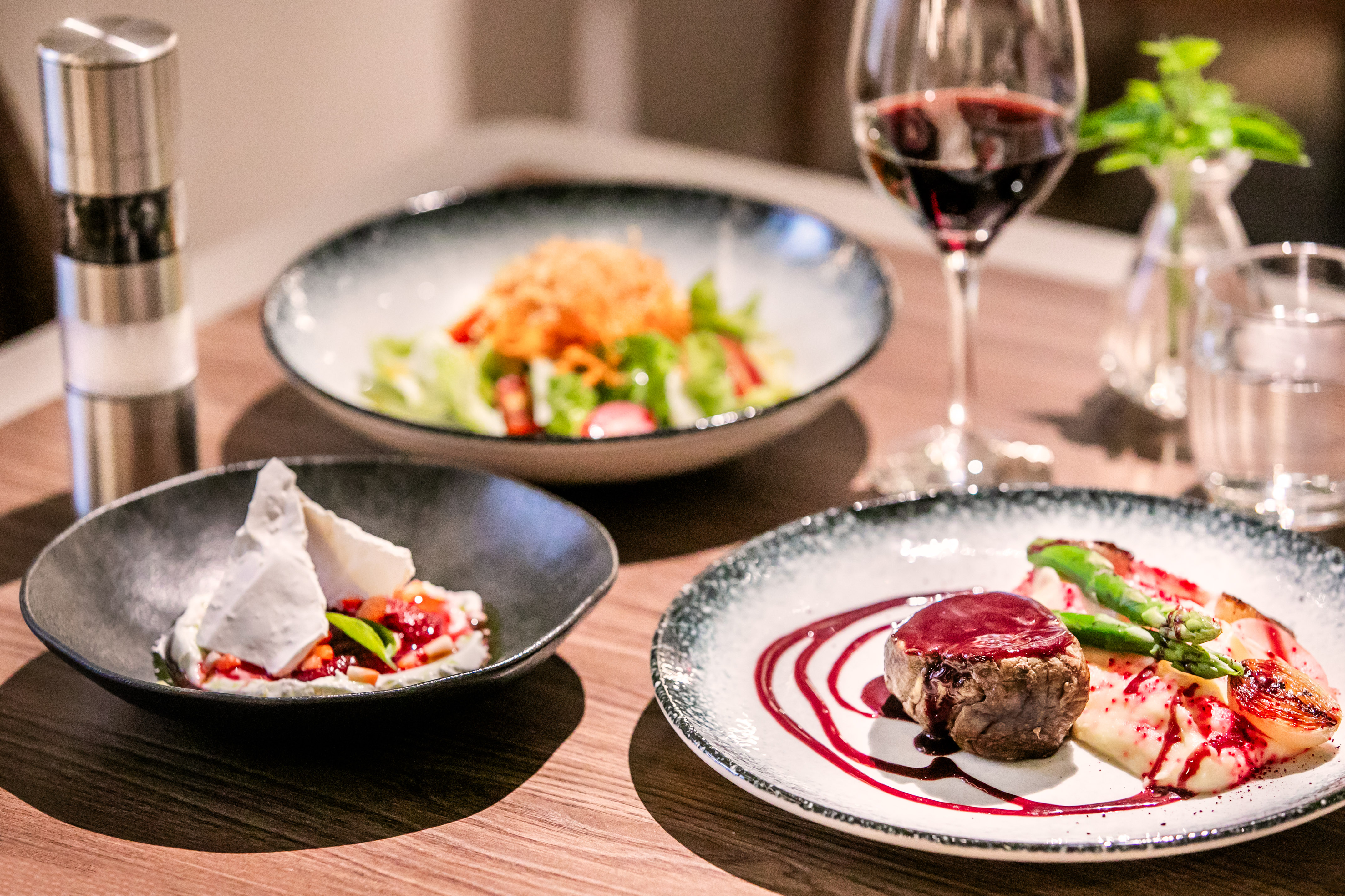 a table with plates of food and a glass of wine