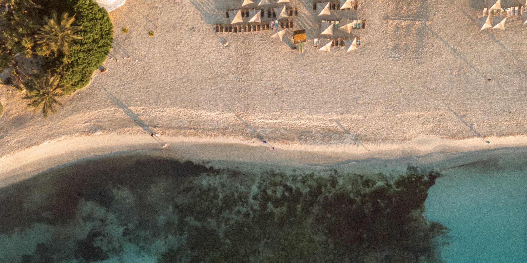 an aerial view of a beach with umbrellas and trees