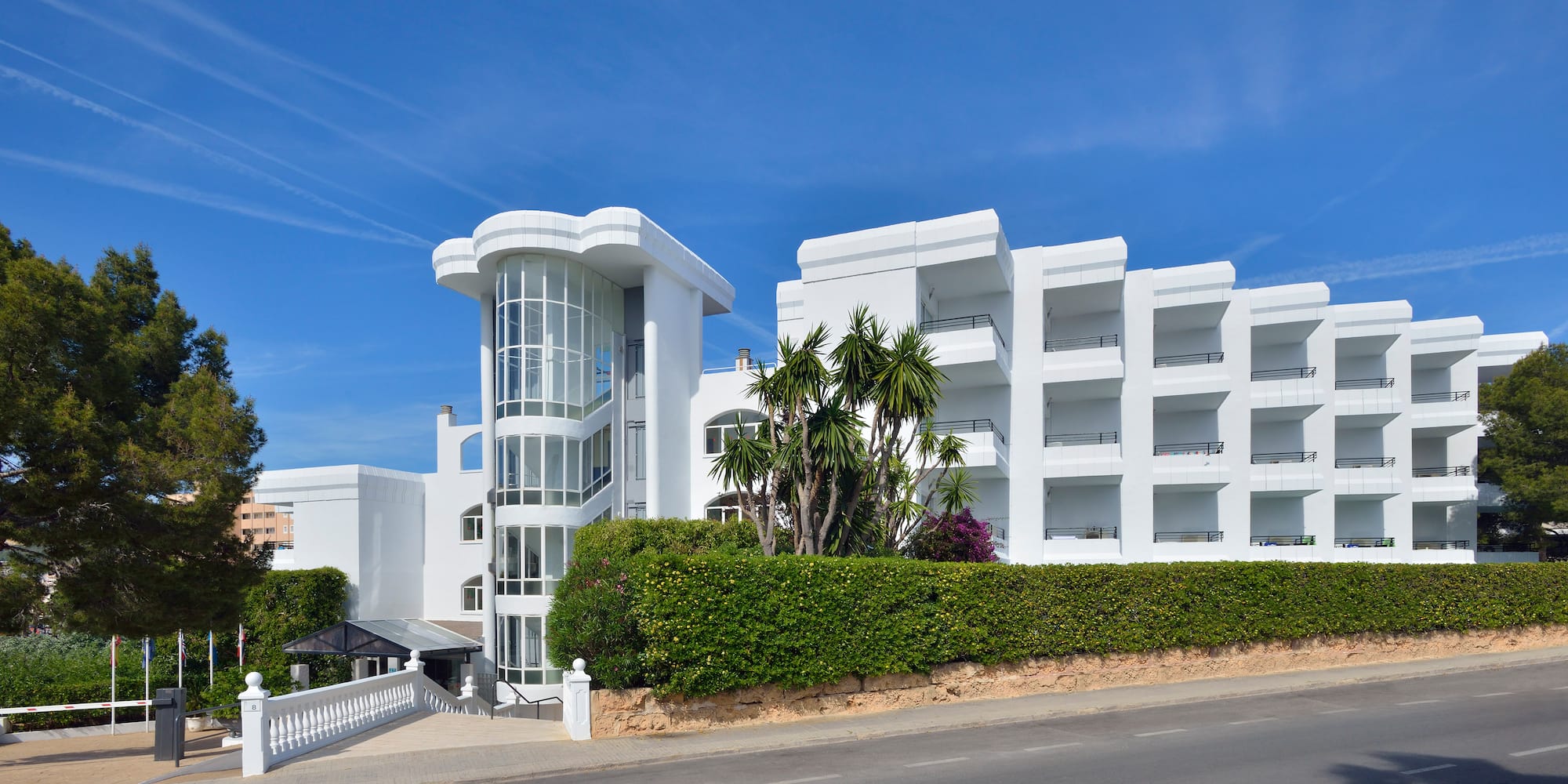 a white building with a hedge and bushes