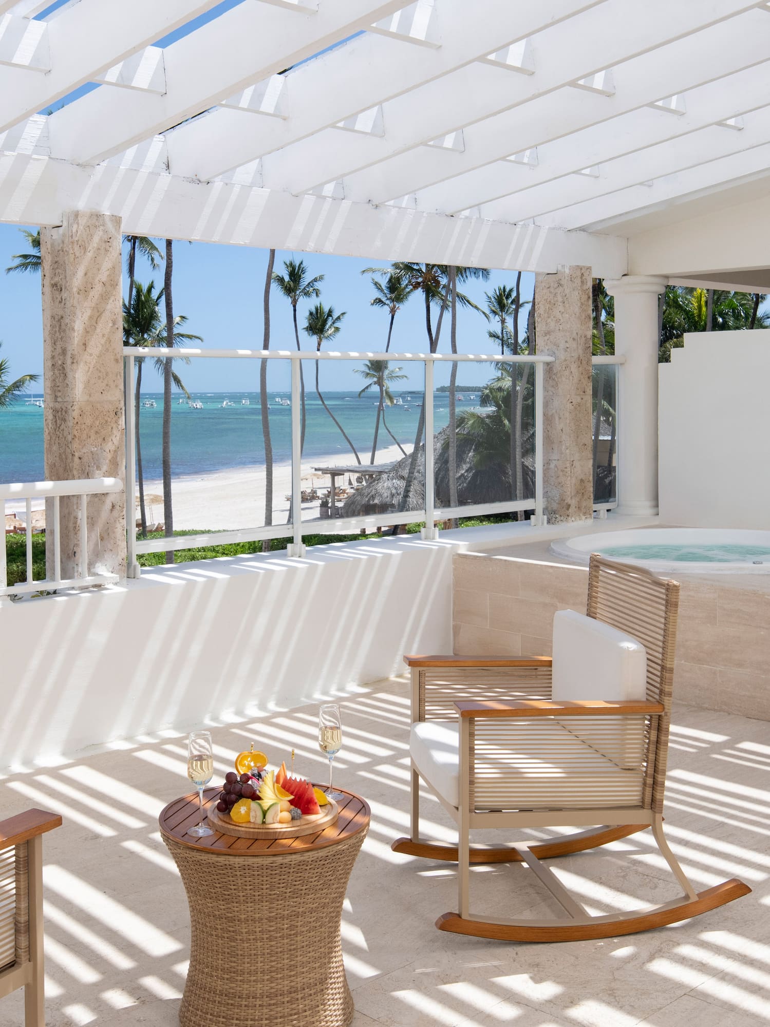 Luxury ocean view balcony with hot tub, palm trees, and tropical beach.