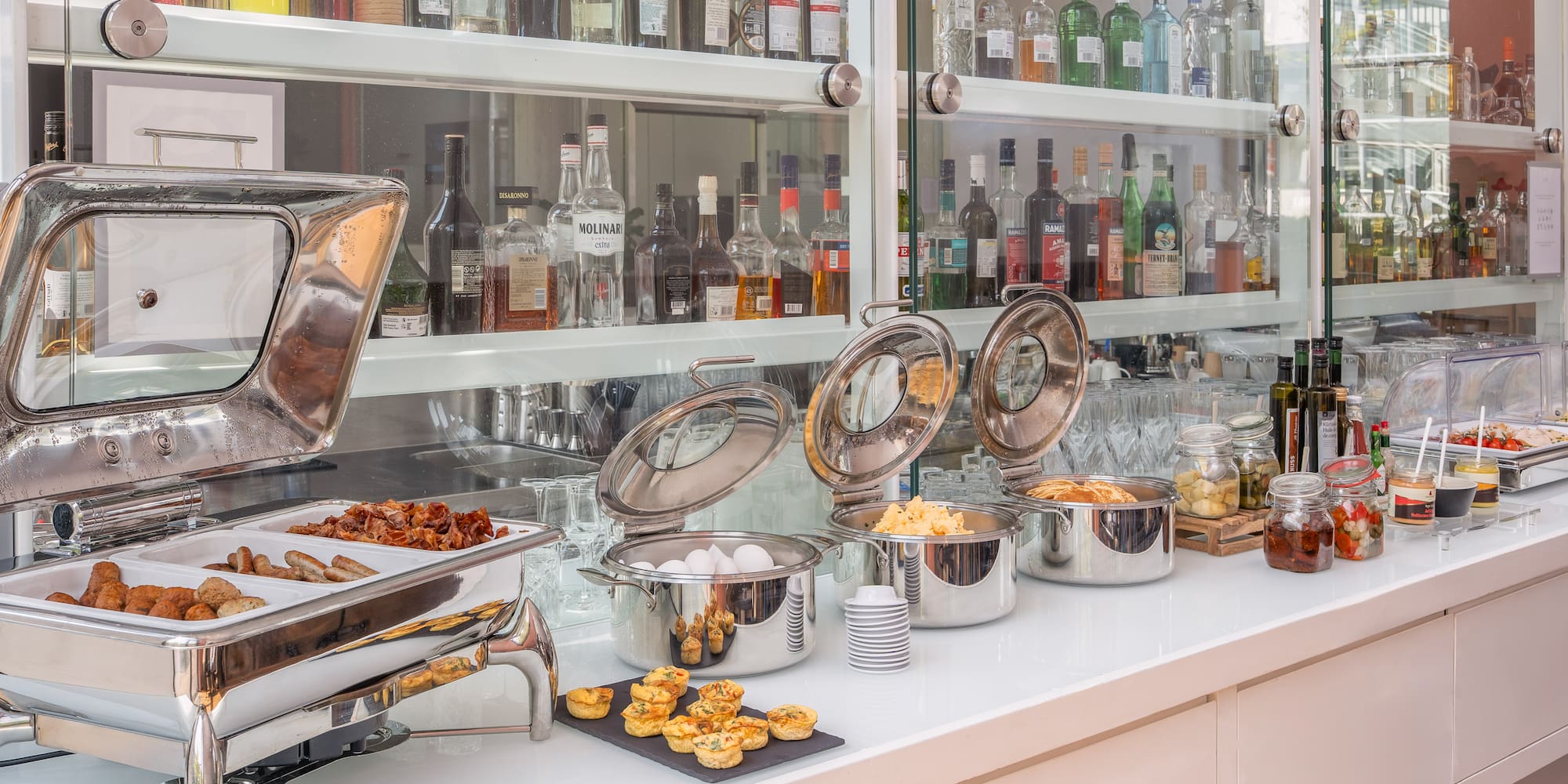 Hotel breakfast buffet: hot food, scrambled eggs, sausages, bacon, quiches, bar.