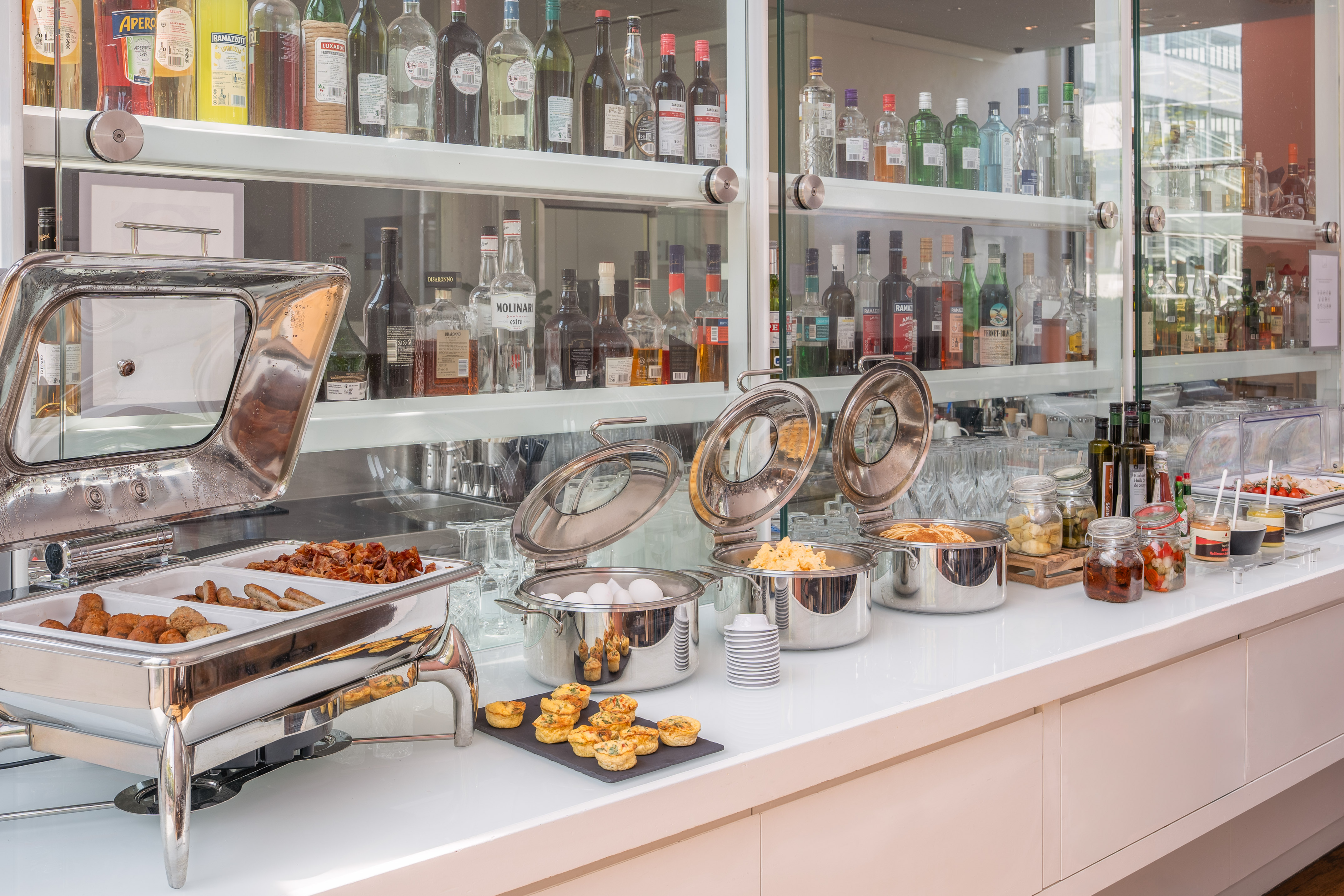 Hotel breakfast buffet: hot food, scrambled eggs, sausages, bacon, quiches, bar.