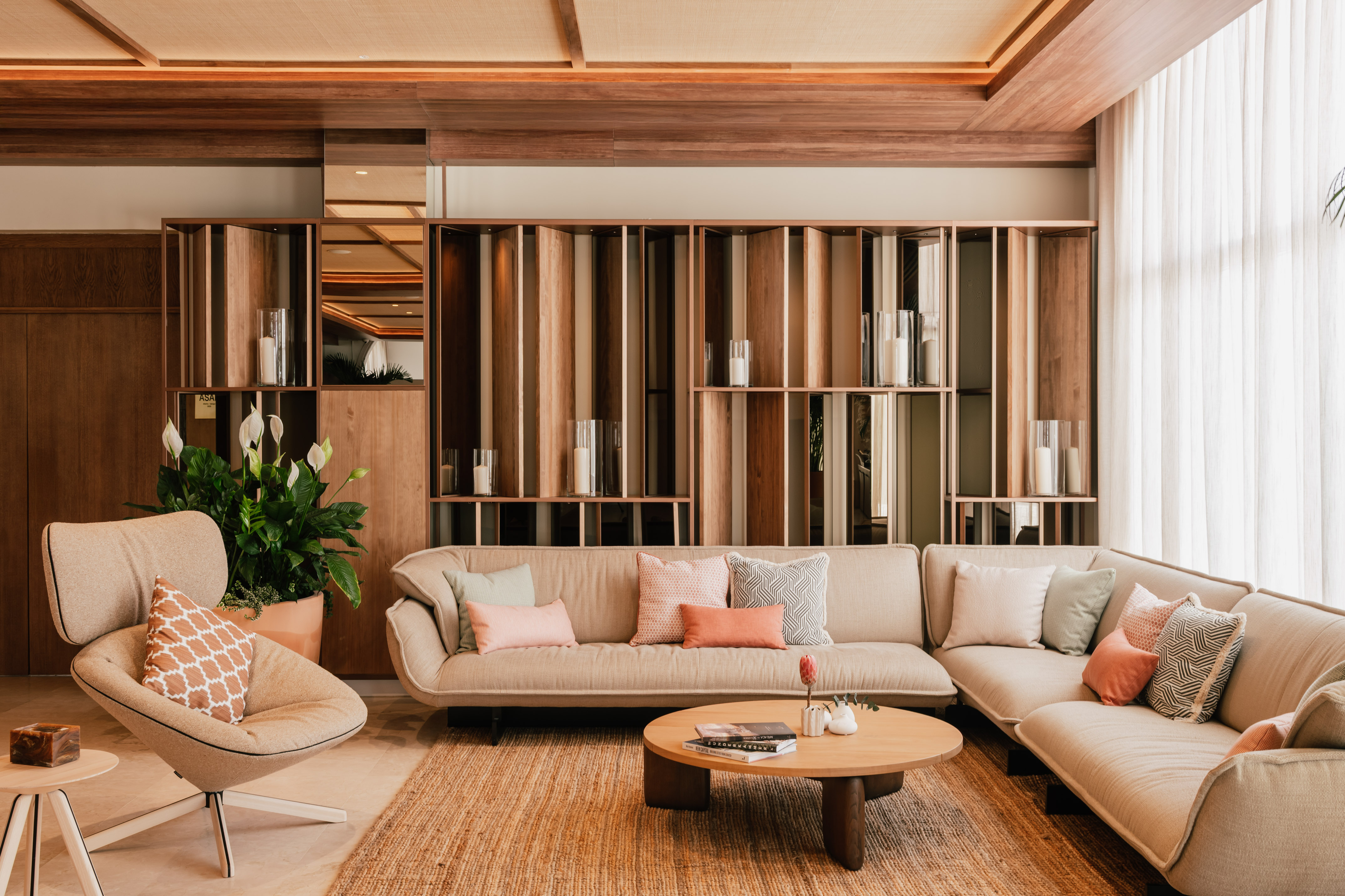 Modern living room with neutral sectional sofa, wooden shelves, and cozy rug.