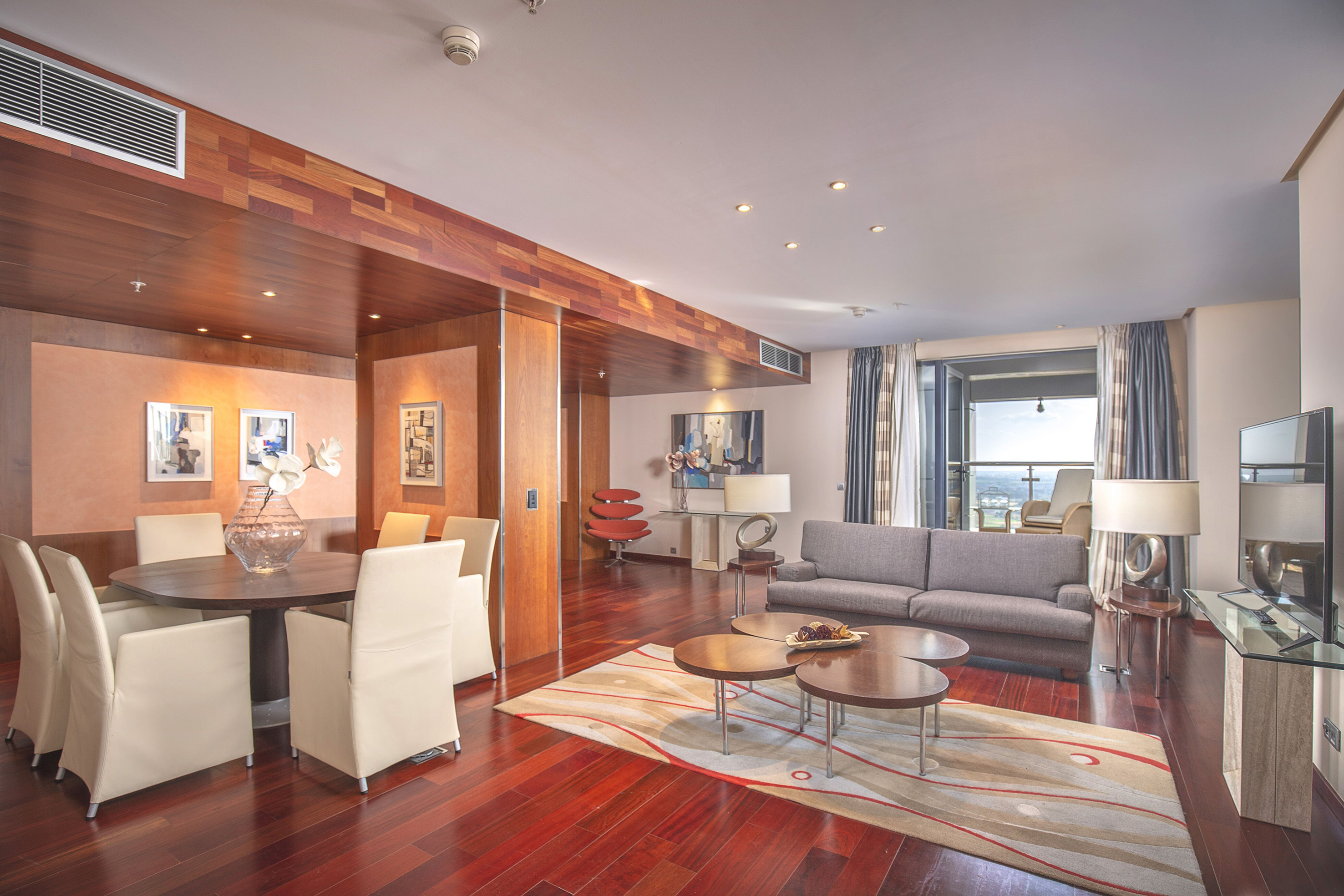 Modern open-plan living and dining room with hardwood floors and balcony.