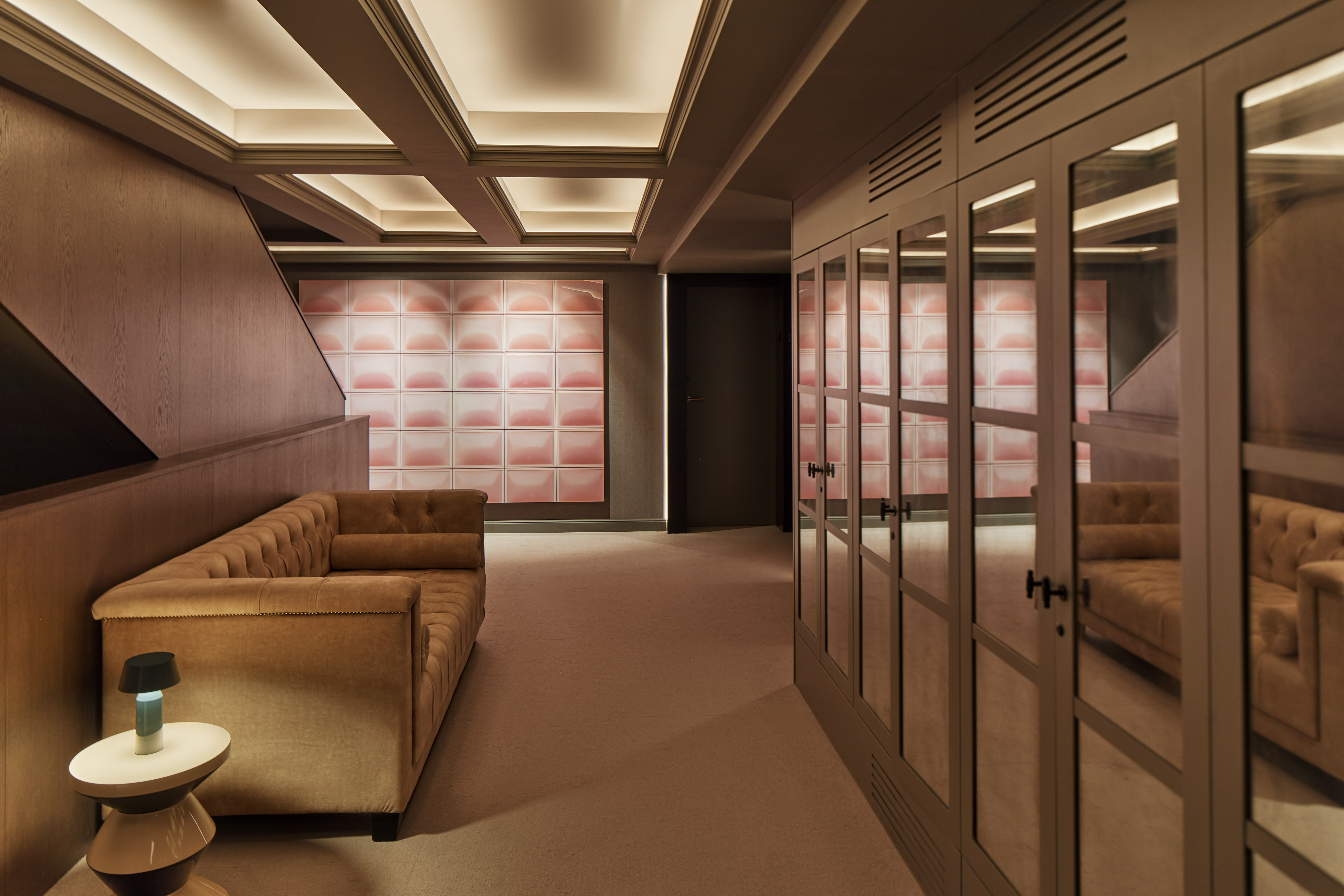 Velvet sofa, mirrored closets, and lit coffered ceiling in modern interior.