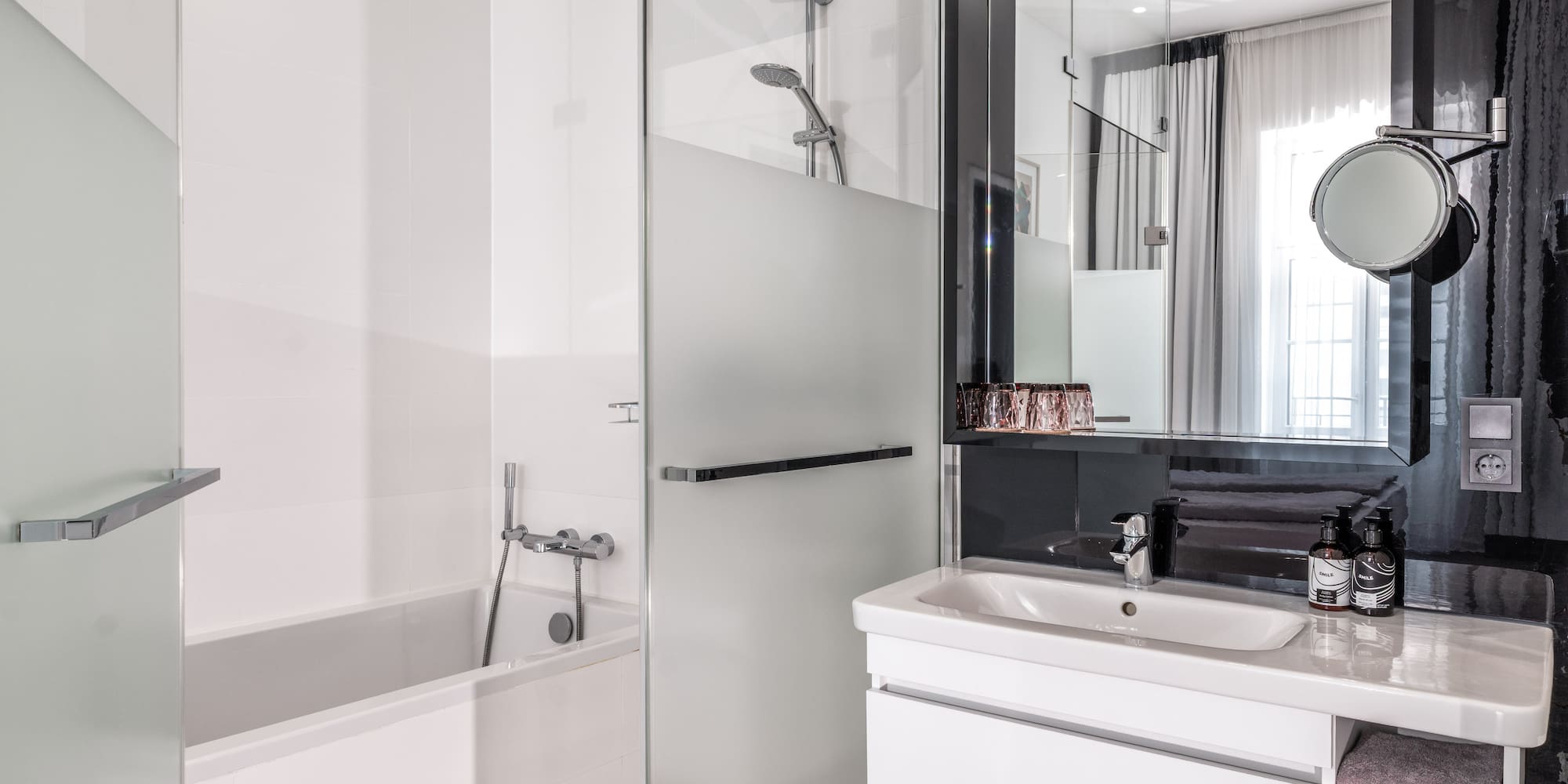 Clean, modern hotel bathroom with white bathtub, glass shower, and vanity.