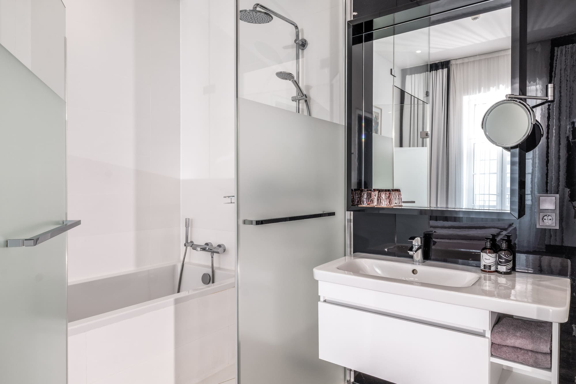 Clean, modern hotel bathroom with white bathtub, glass shower, and vanity.