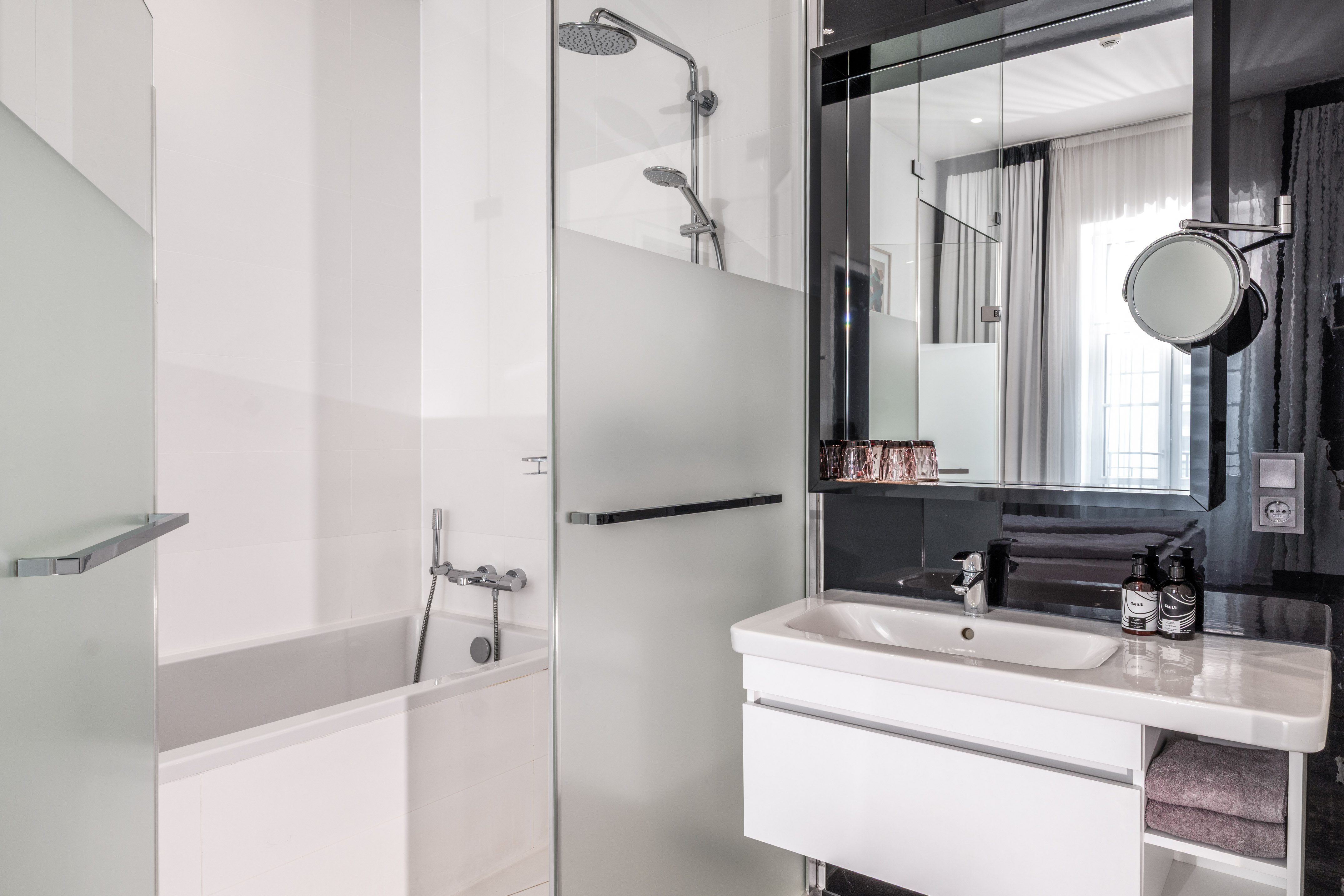 Clean, modern hotel bathroom with white bathtub, glass shower, and vanity.