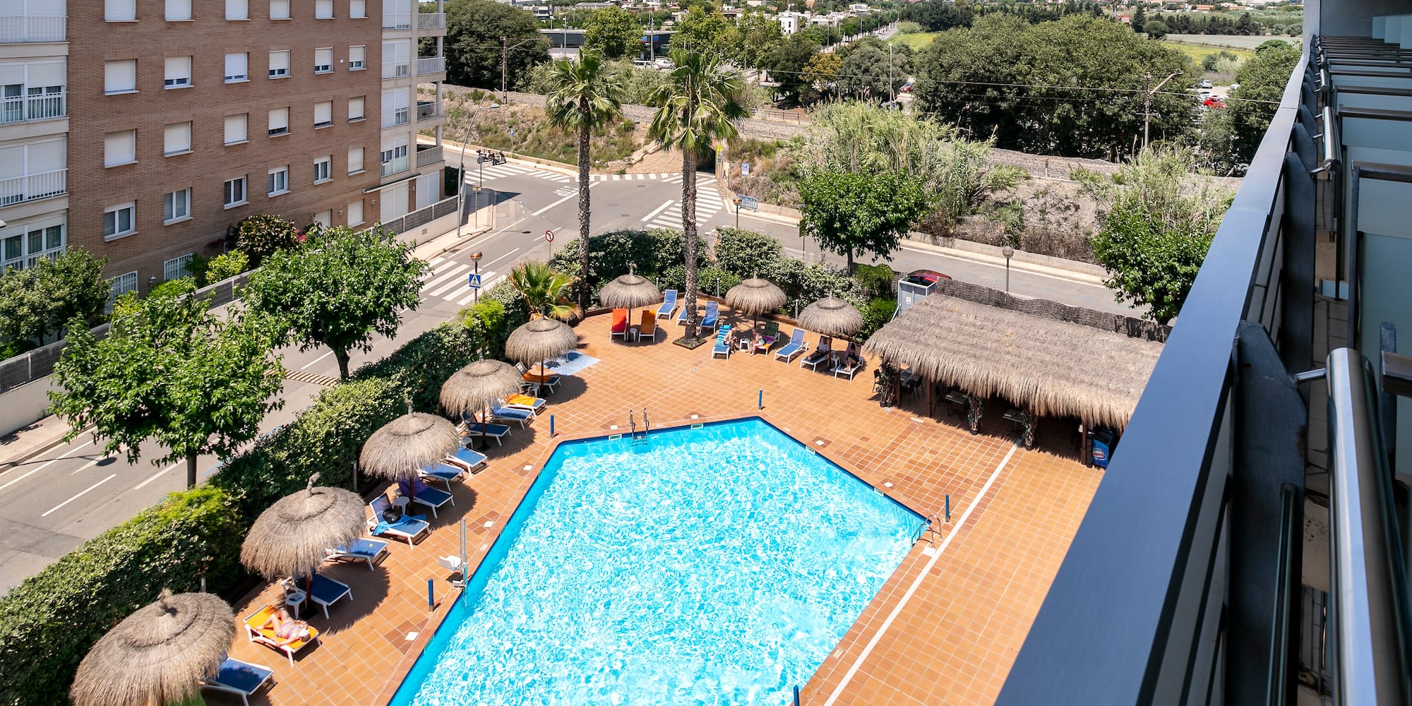 a pool with straw umbrellas and a building in the background