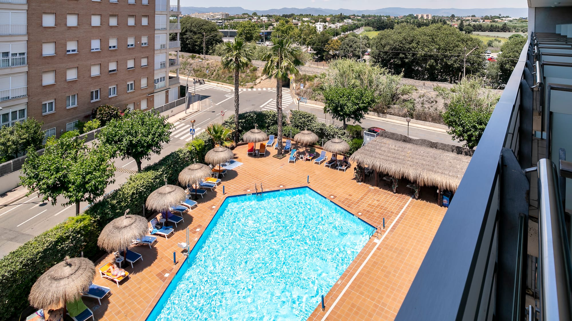 a pool with straw umbrellas and a building in the background