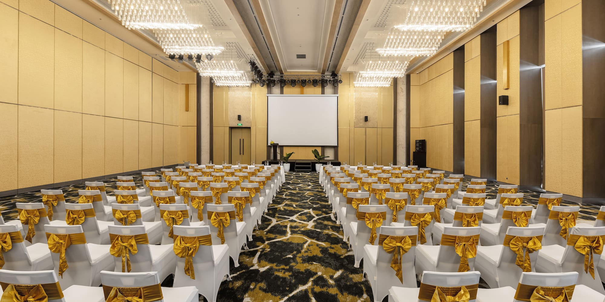 a room with white chairs with gold bows