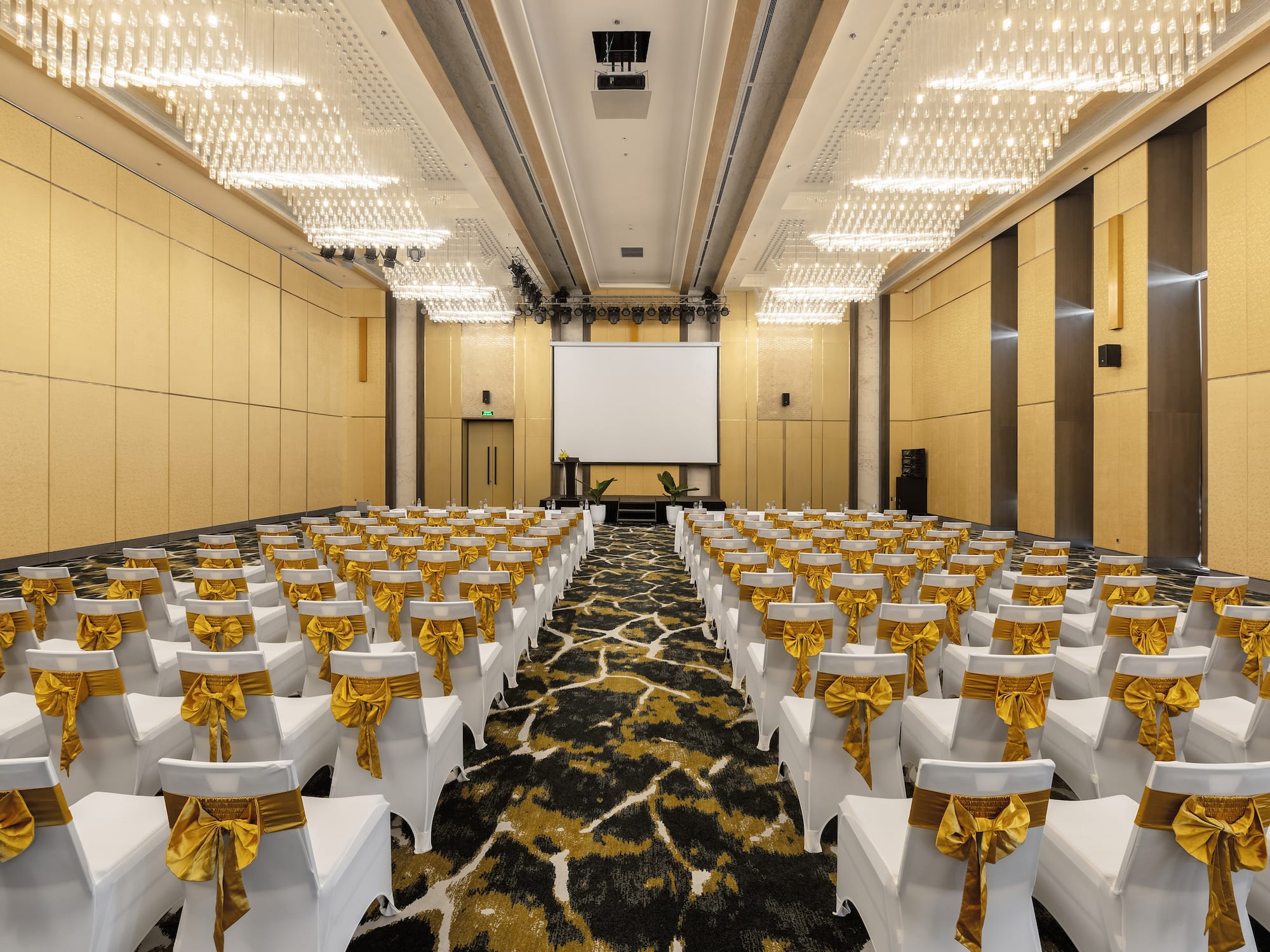 a room with white chairs with gold bows