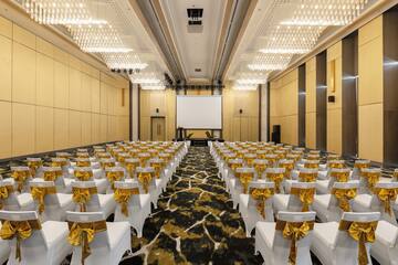 a room with white chairs with gold bows