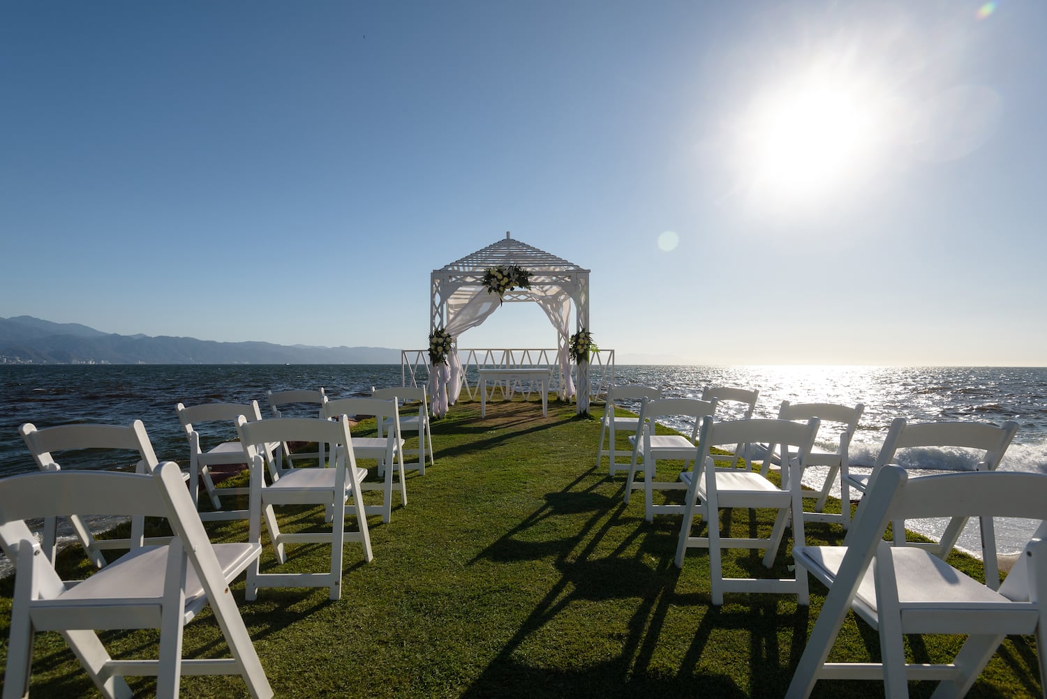 a wedding ceremony set up on a grassy area with white chairs