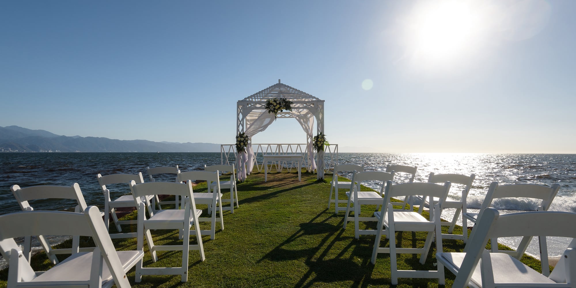 a wedding ceremony set up on a grassy area with white chairs