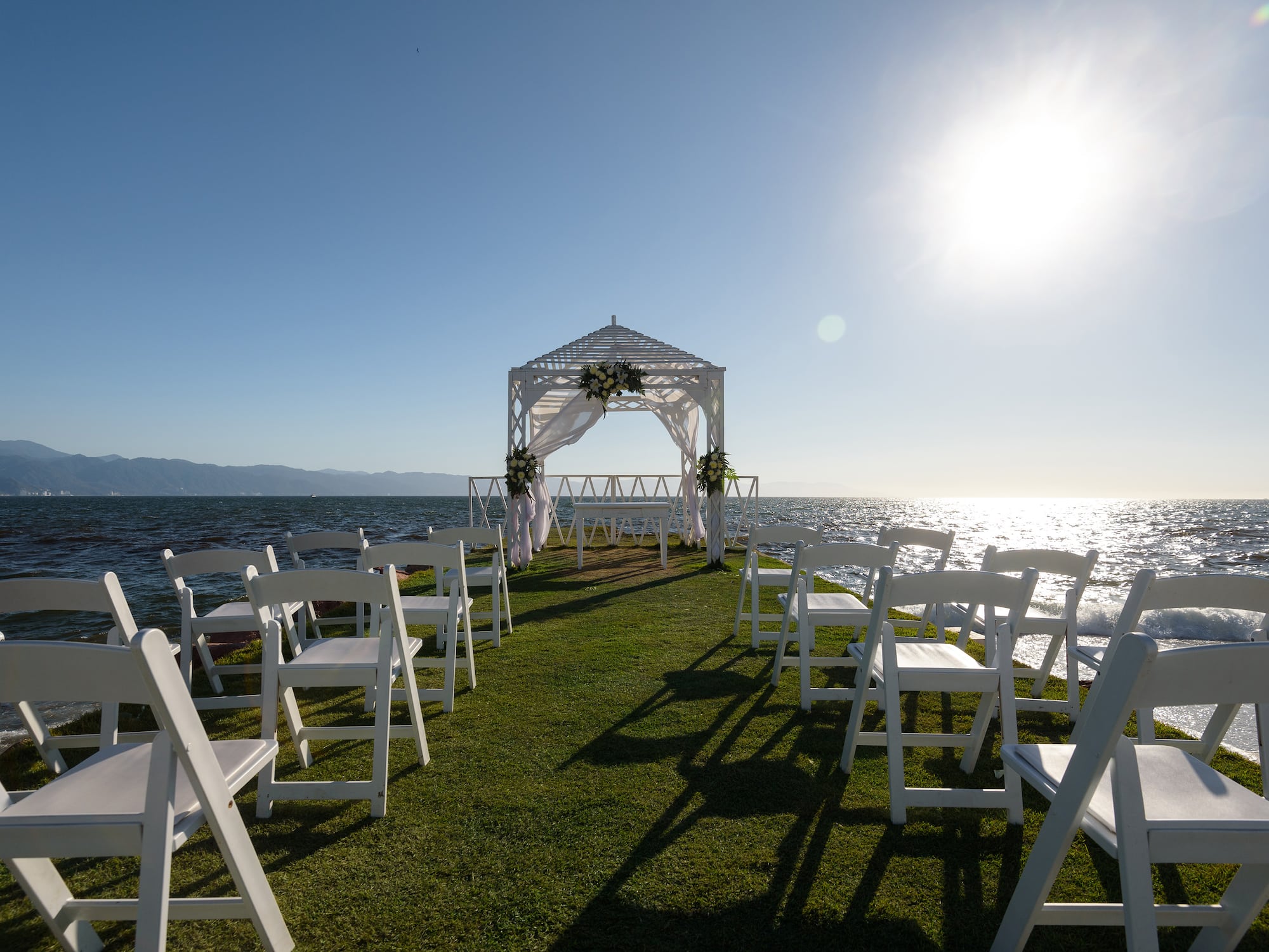 a wedding ceremony set up on a grassy area with white chairs