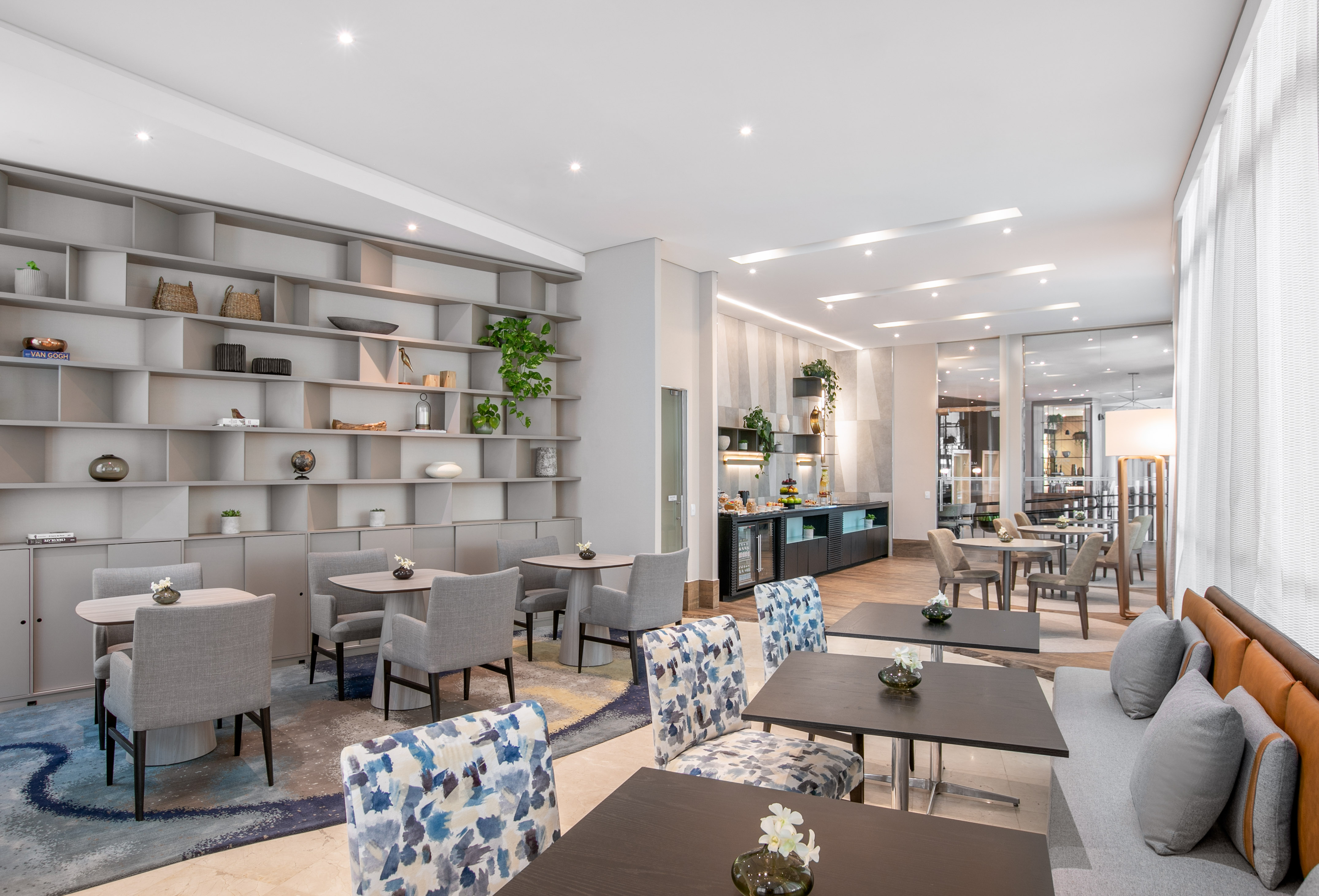 Modern hotel lounge with stylish seating, buffet, and decorative shelving.