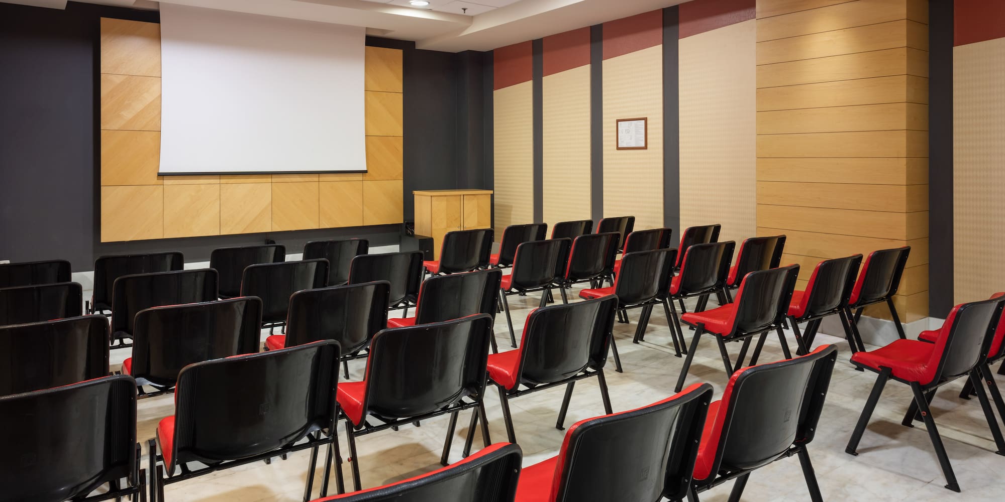 Conference room with red and black chairs, projection screen, and projector.