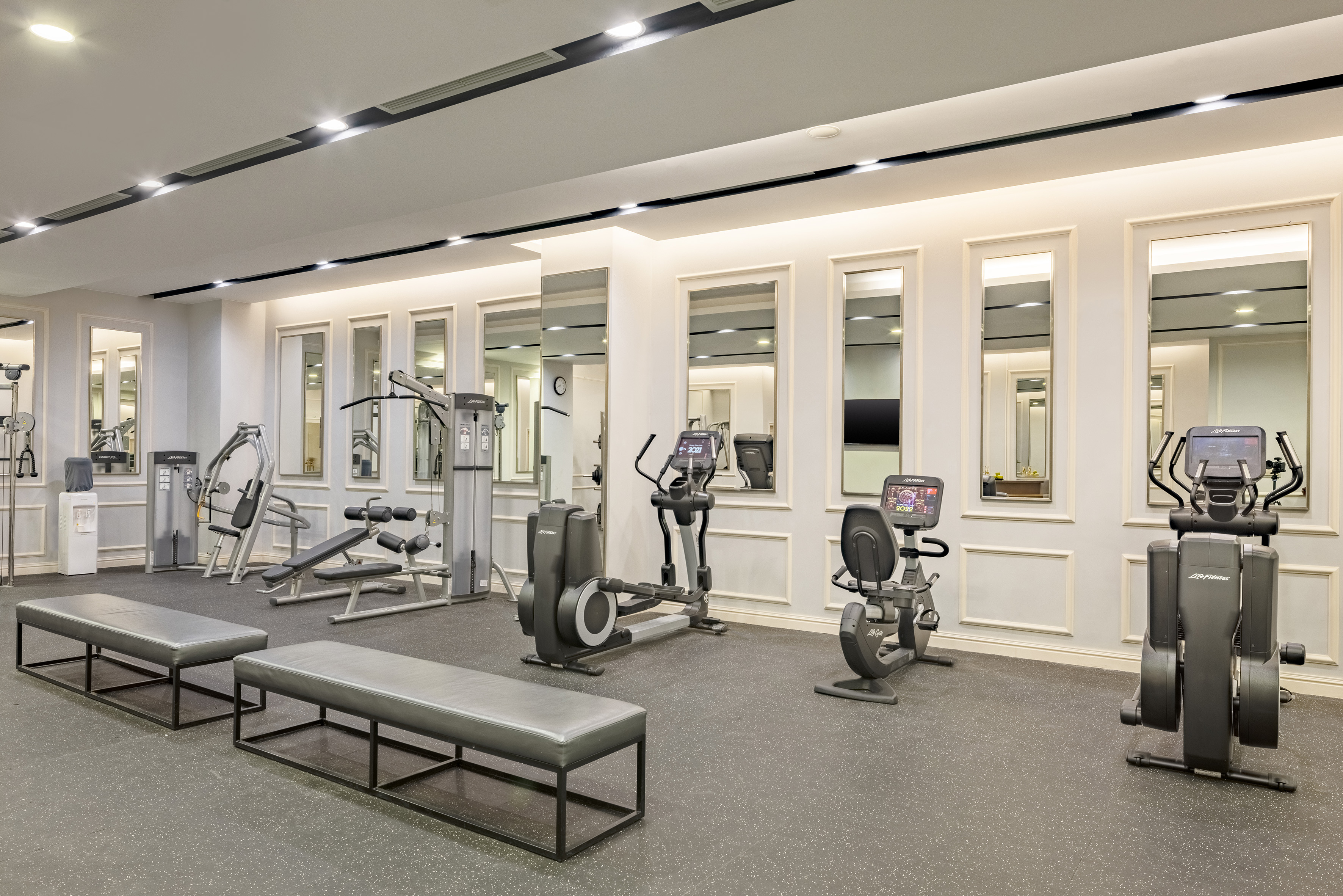 Sleek hotel gym featuring elliptical, recumbent bike, weight stations, and benches.