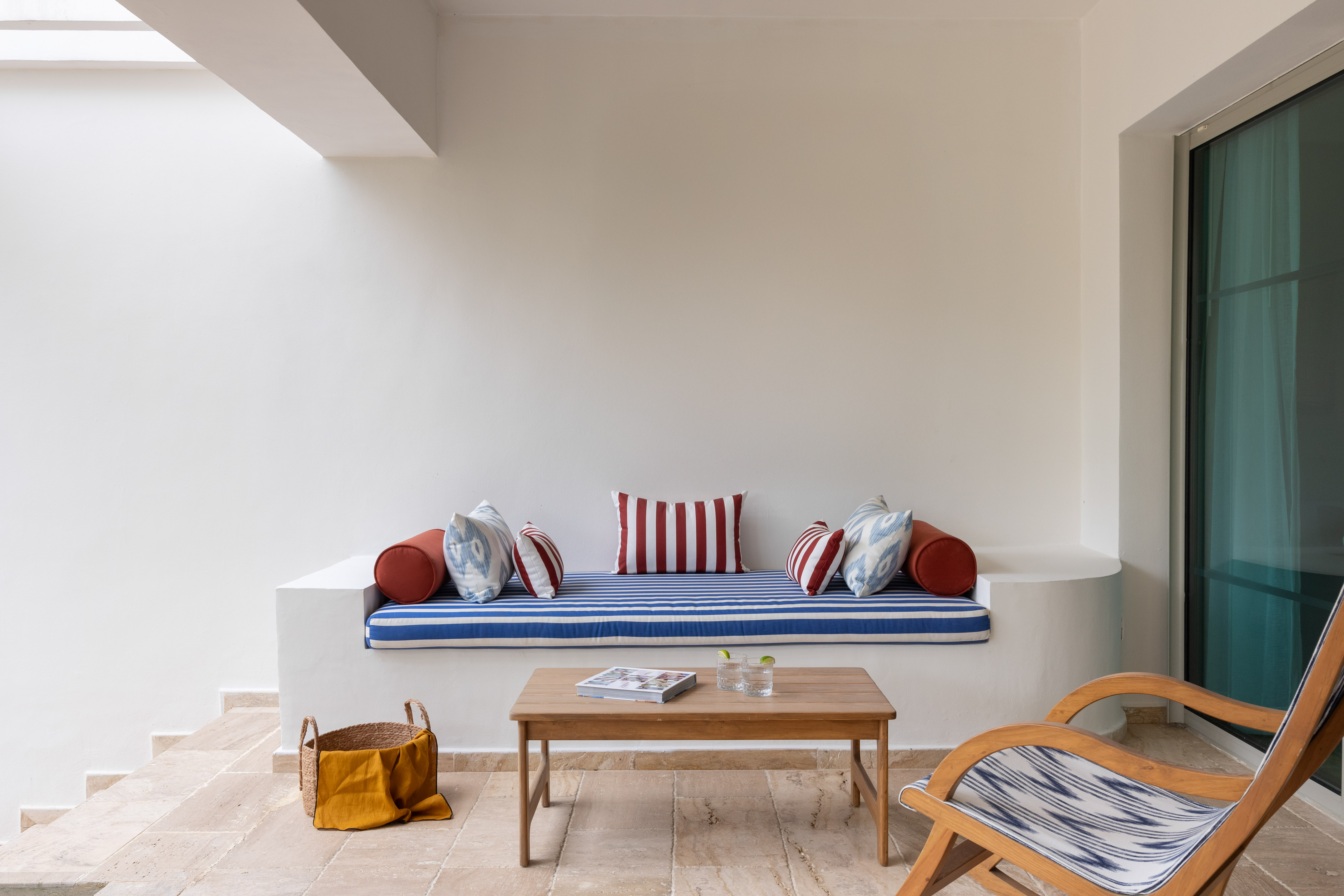 Outdoor patio with blue striped bench, red cushions, wooden coffee table.