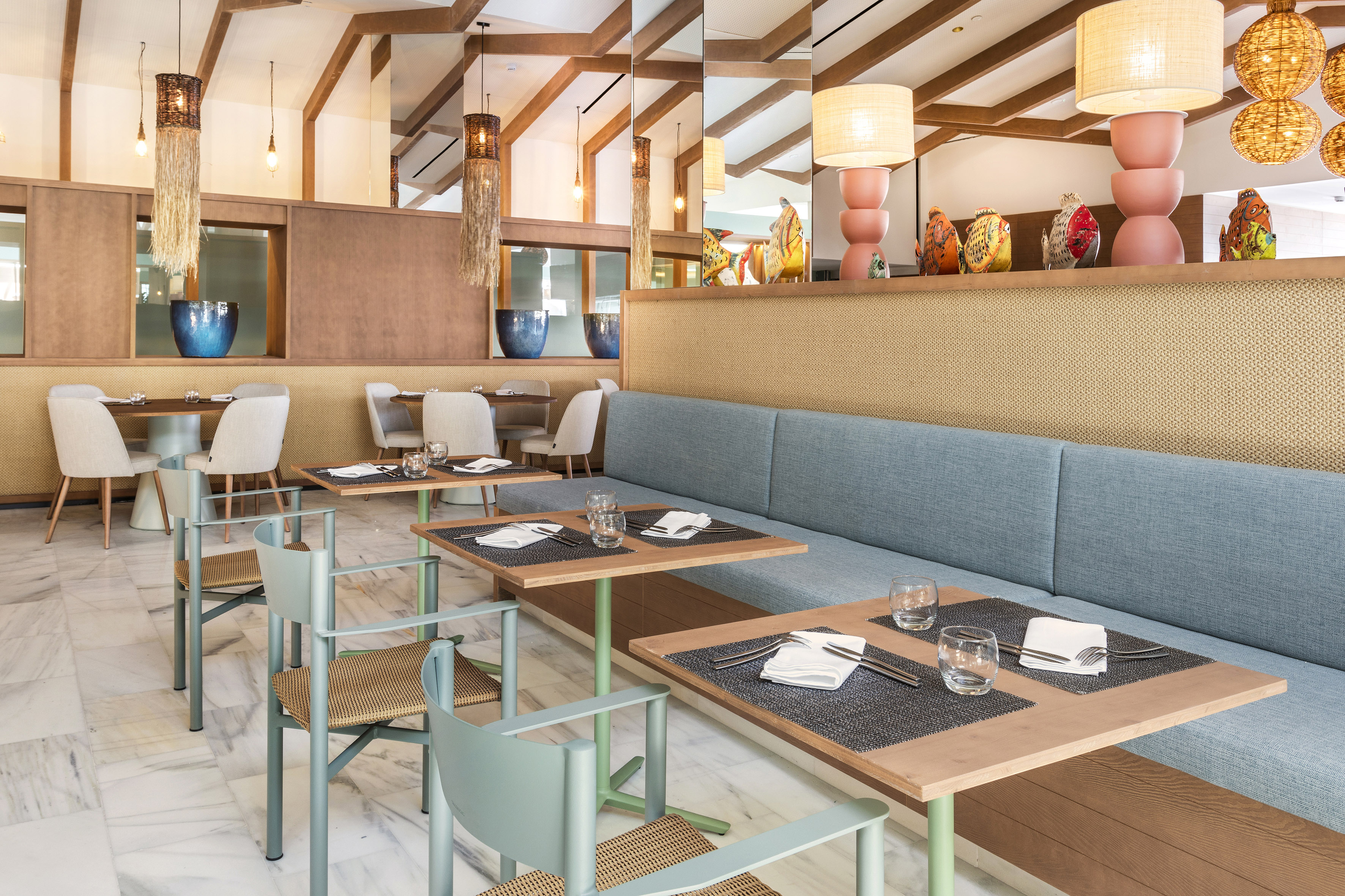 Modern restaurant dining room with blue banquette seating and stylish lighting.