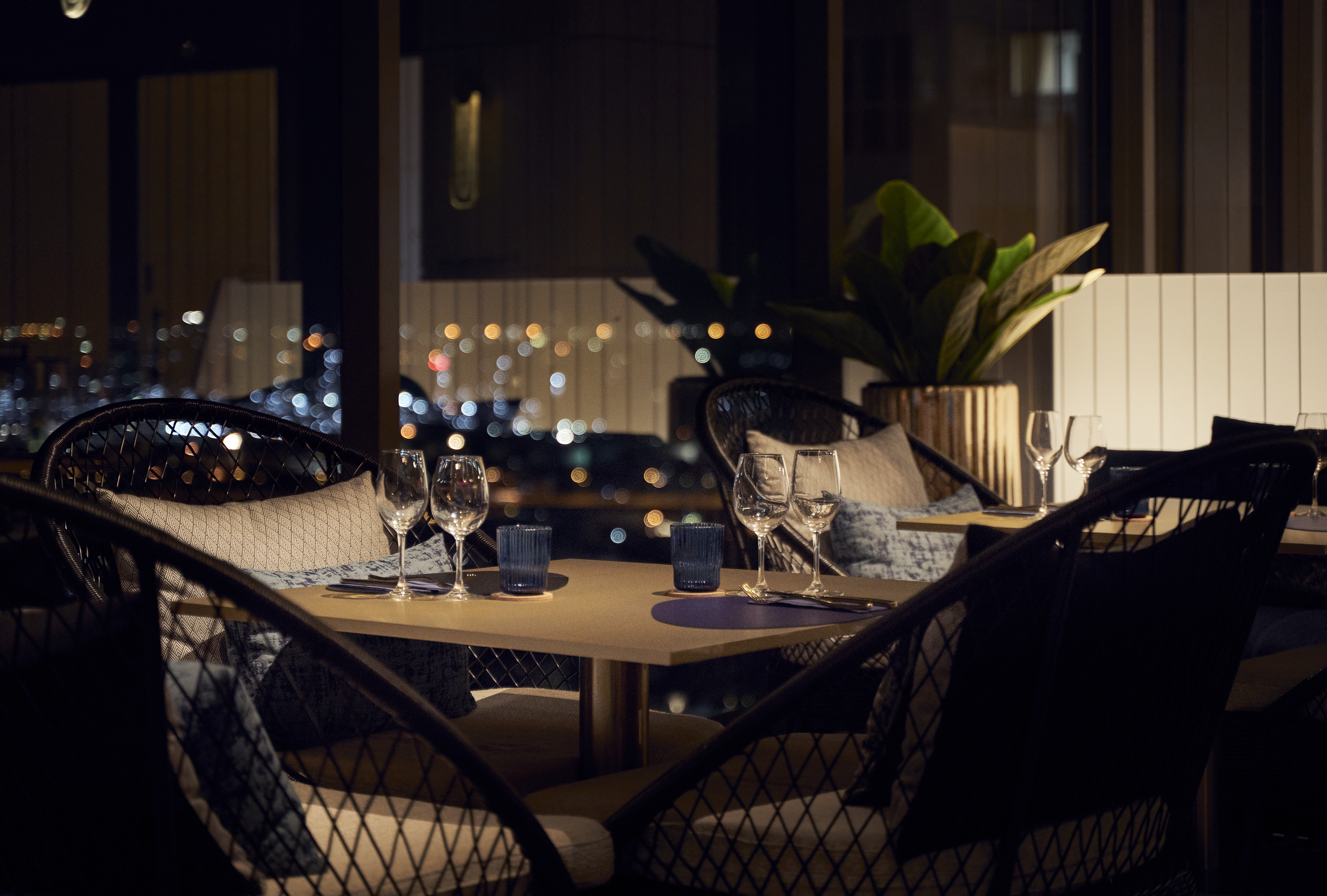 Upscale restaurant with city night view, tables set for fine dining.