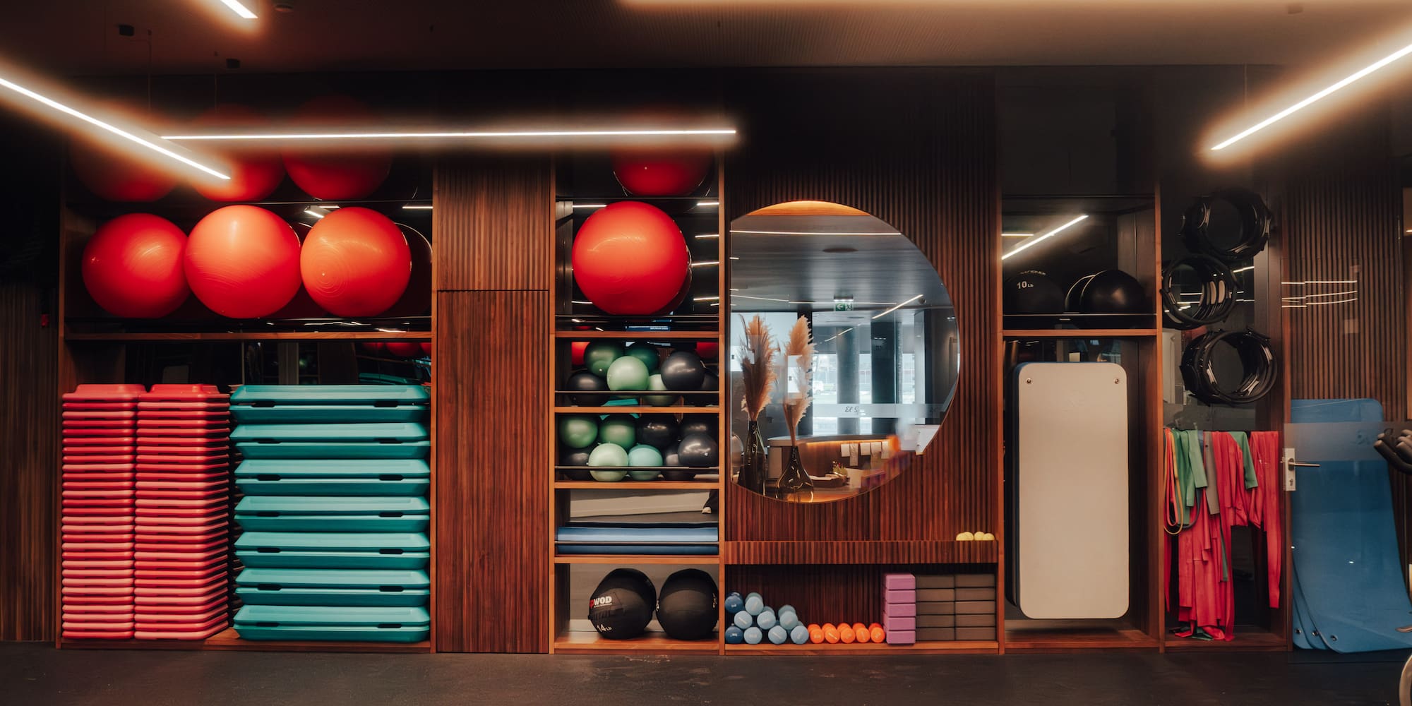 Organized gym with red stability balls, teal steps, and fitness equipment.