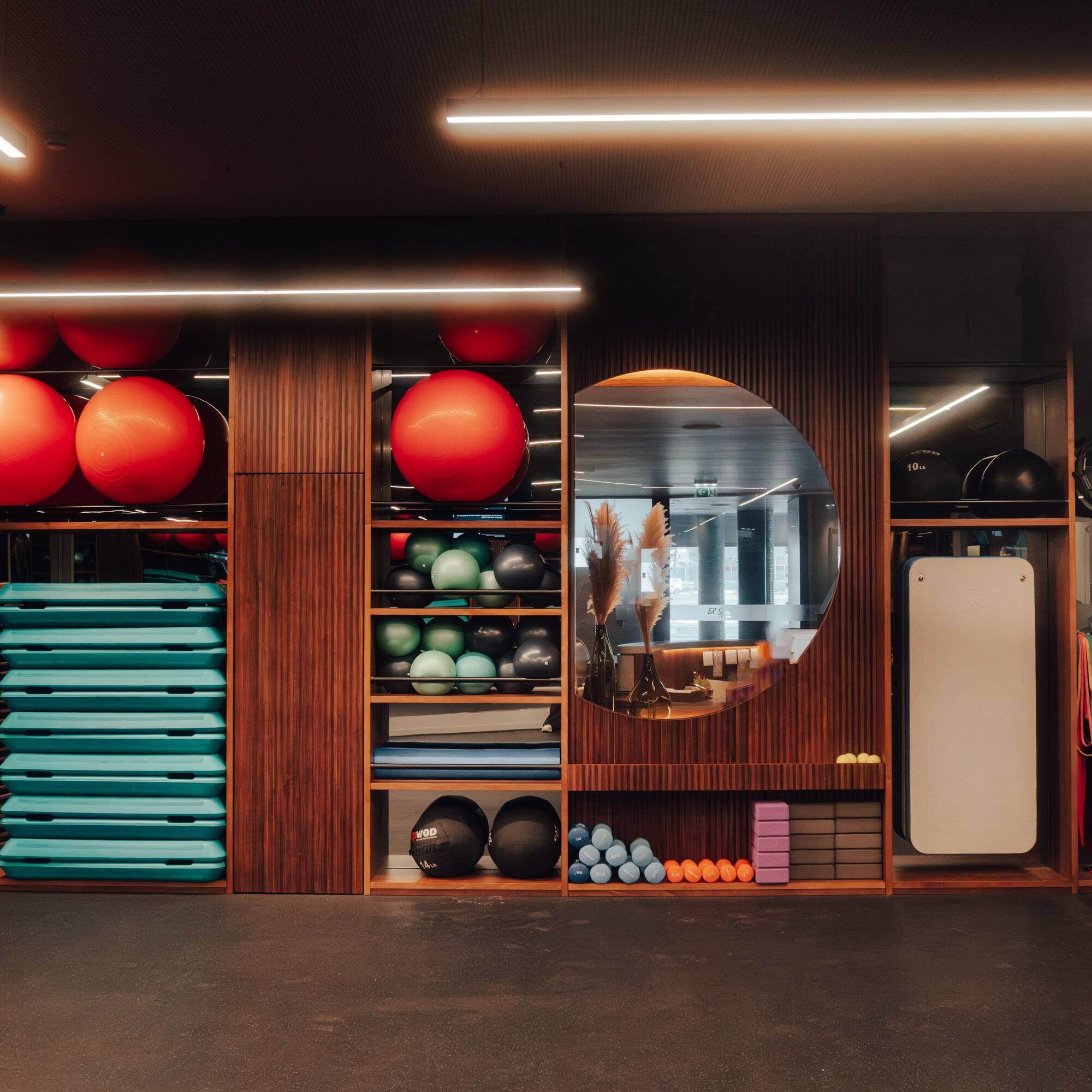 Organized gym with red stability balls, teal steps, and fitness equipment.